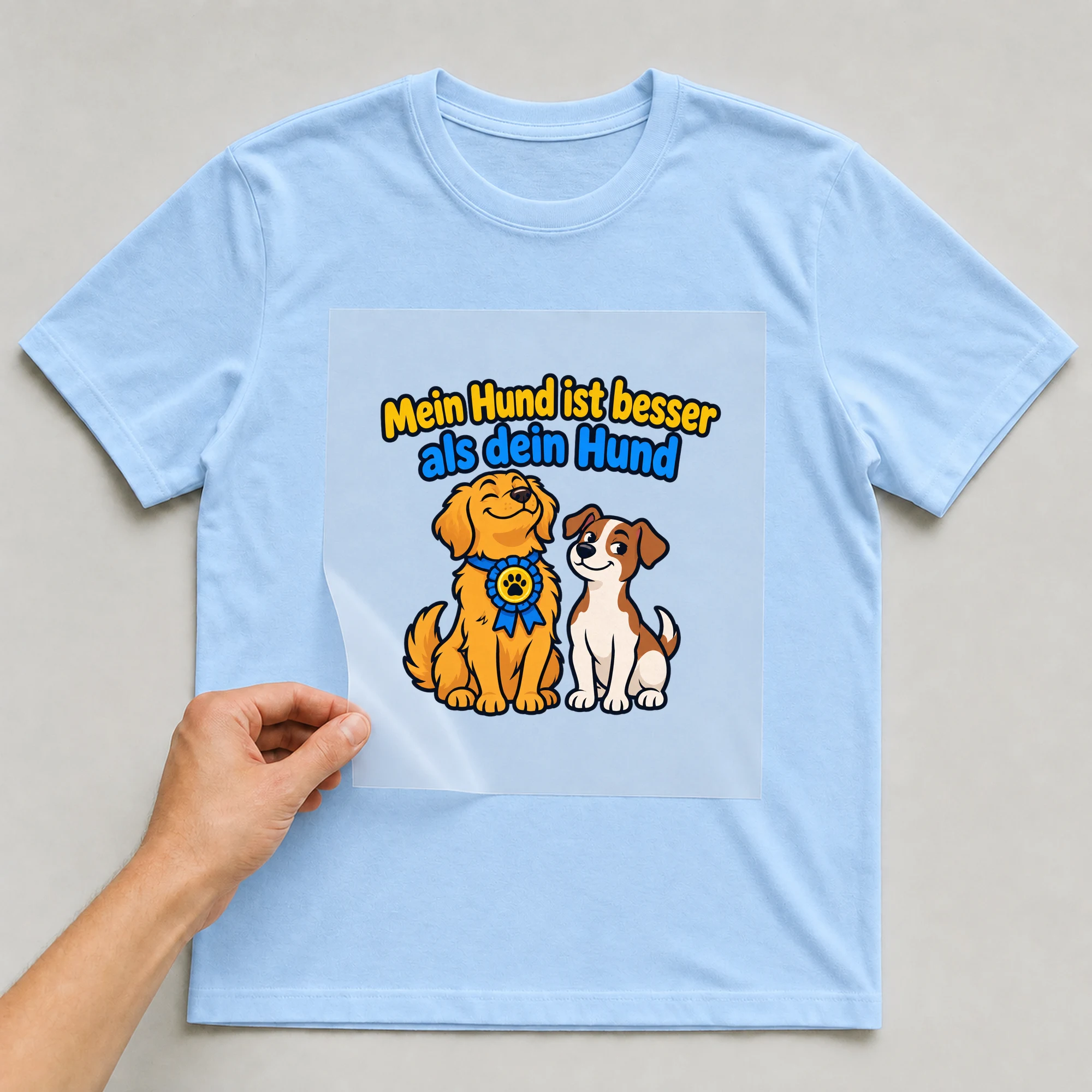 Bügelbild „Mein Hund ist besser als dein Hund“ auf babyblauem T-Shirt, Folie wird aufgelegt
