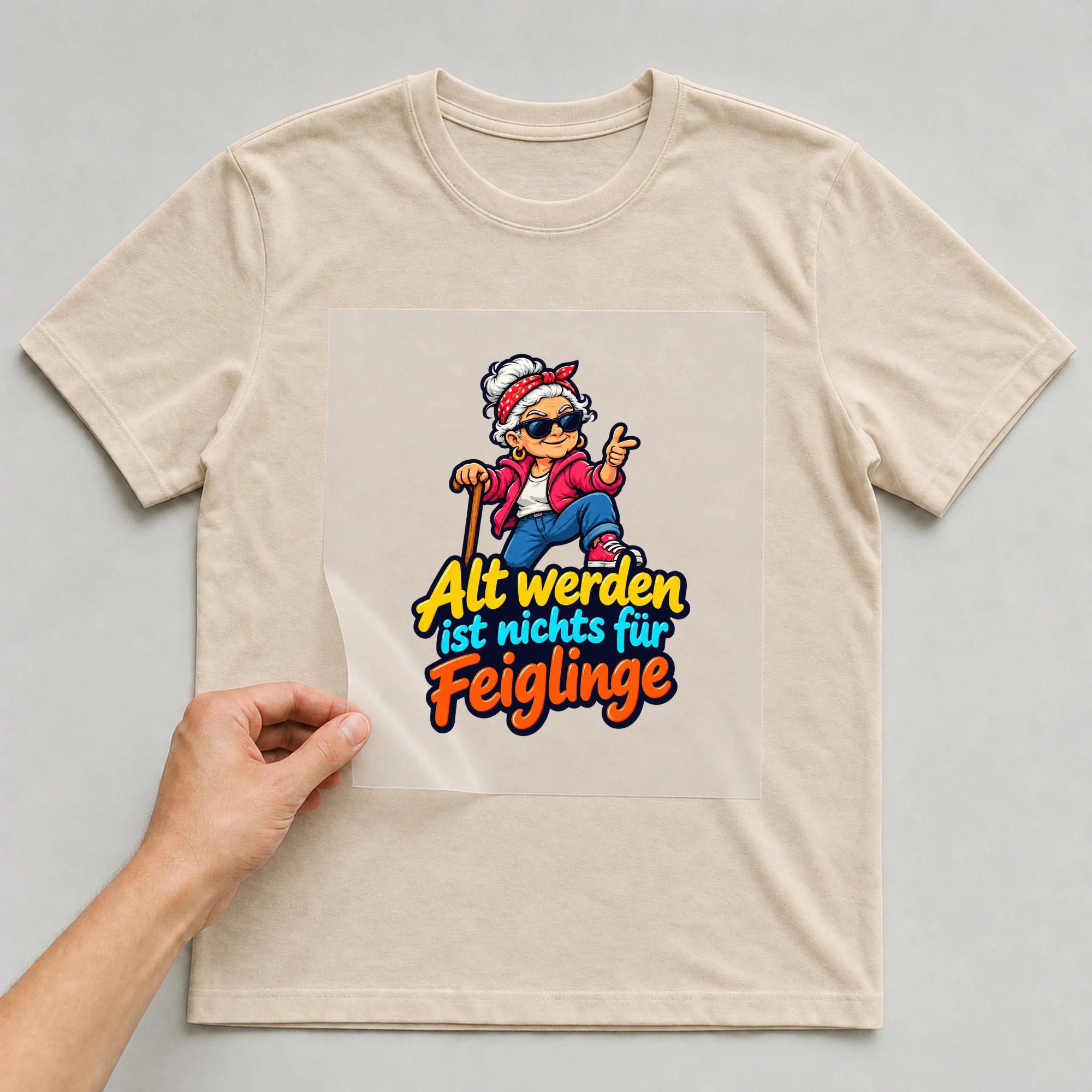 Bügelbild „Alt werden ist nichts für Feiglinge“ auf beigem T-Shirt, Folie wird aufgelegt