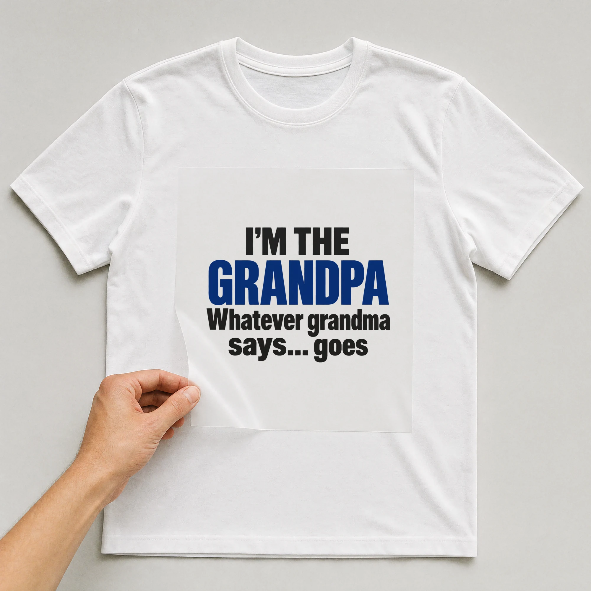 Bügelbild „I'm The Grandpa Whatever Grandma Says... Goes“ auf weißem T-Shirt, Folie wird aufgelegt
