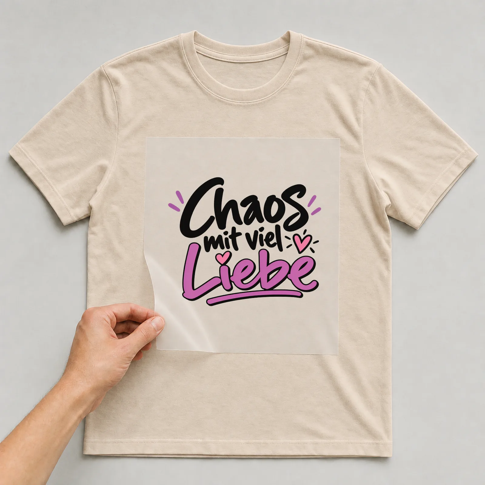 Bügelbild „Chaos mit viel Liebe“ auf beigem T-Shirt, Folie wird aufgelegt