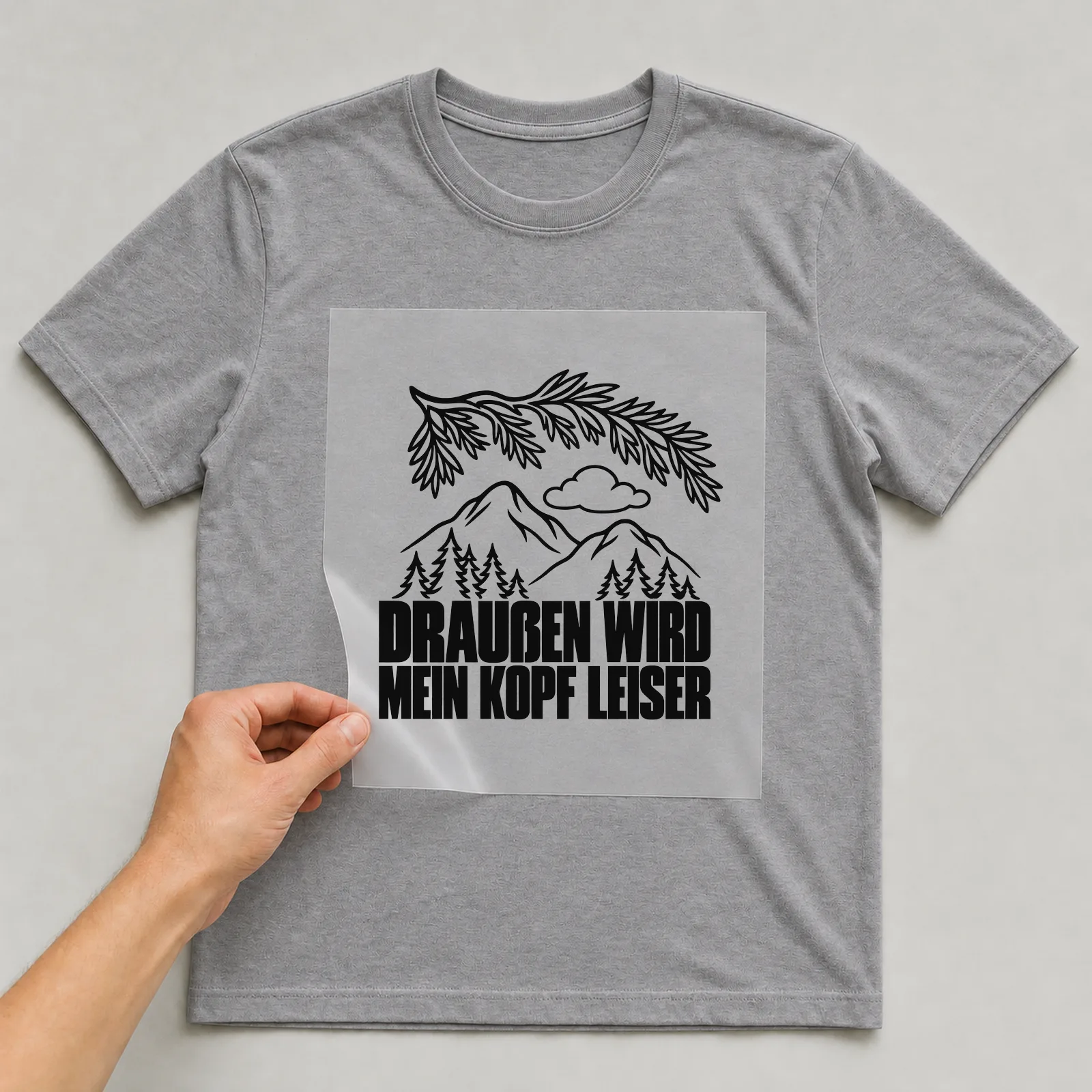 Bügelbild „Draußen wird mein Kopf leiser“ auf grauem T-Shirt, Folie wird aufgelegt