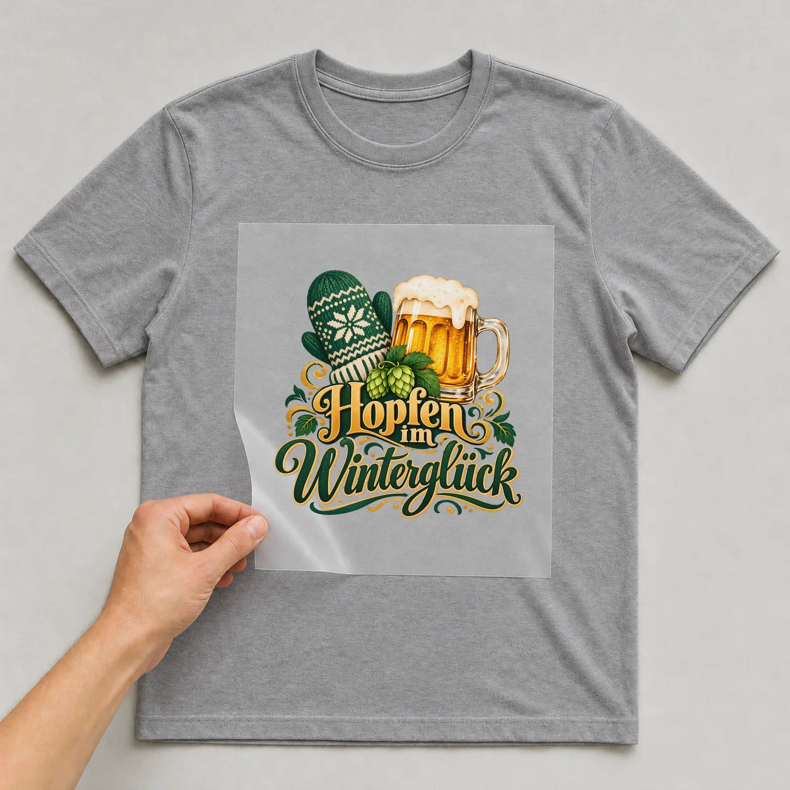 Bügelbild „Hopfen im Winterglück“ auf grauem T-Shirt, Folie wird aufgelegt
