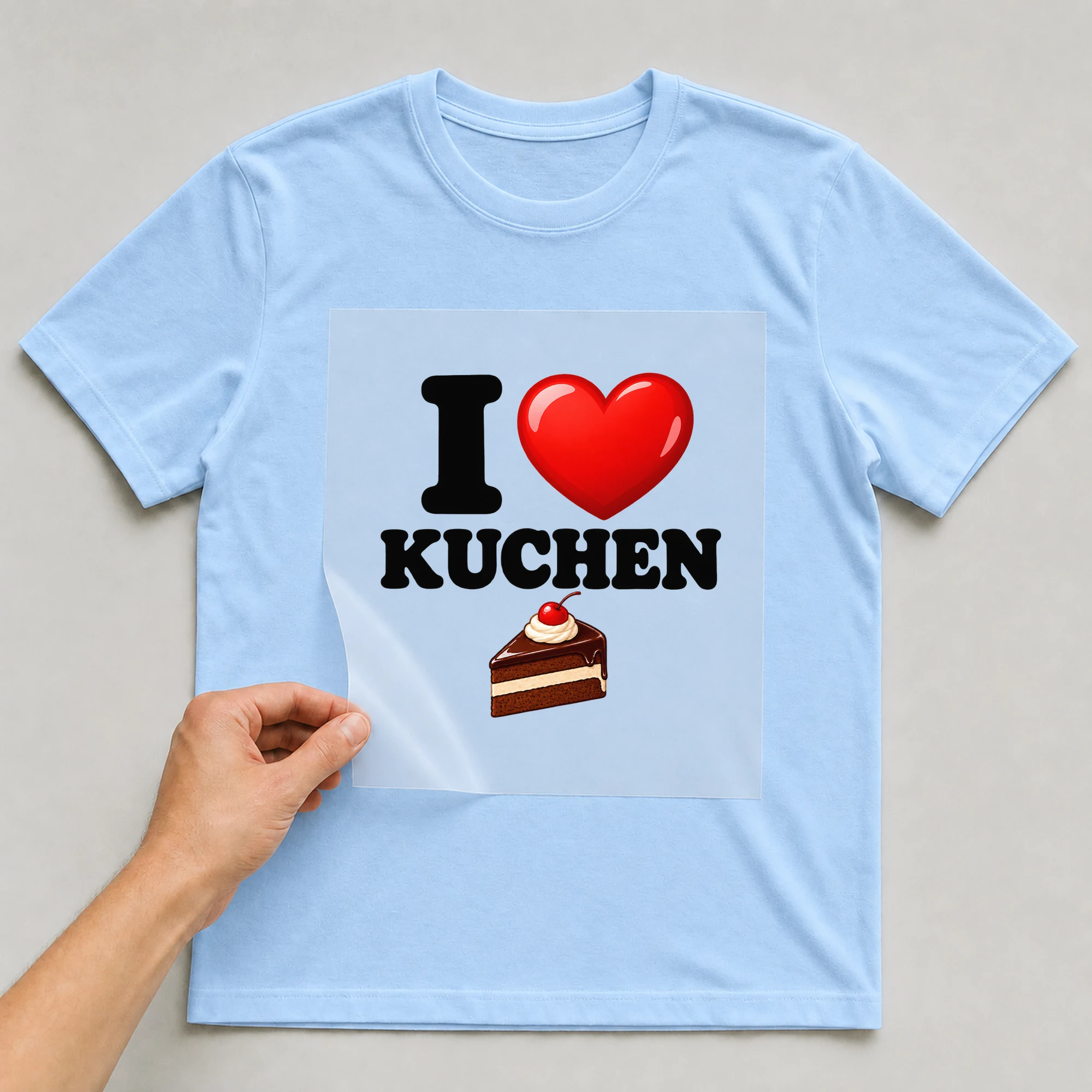 Bügelbild „Kuchenliebe mit Herz“ auf babyblauem T-Shirt, Folie wird aufgelegt