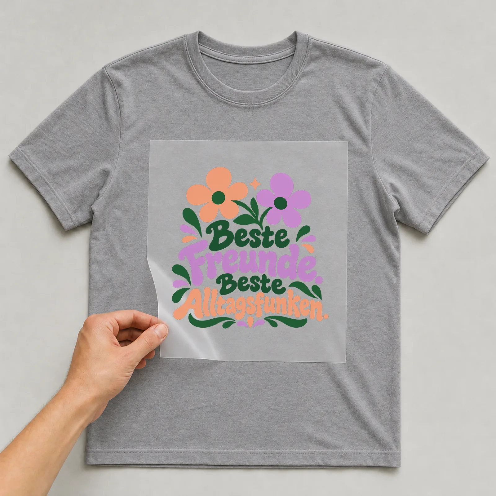 Bügelbild „Beste Freunde. Beste Alltagsfunken.“ auf grauem T-Shirt, Folie wird aufgelegt