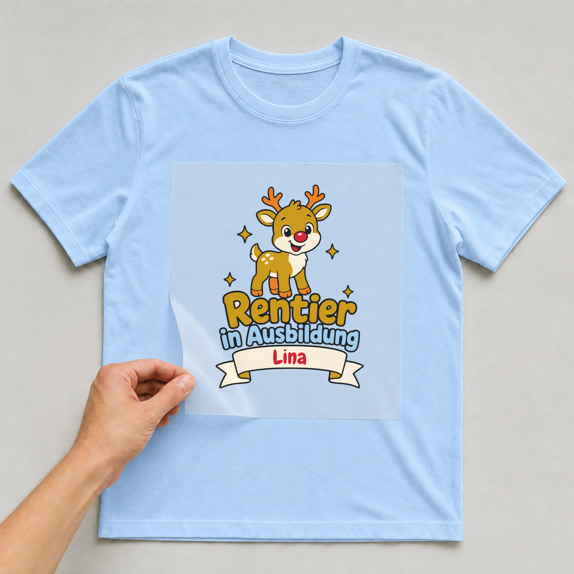 Bügelbild Rentier in Ausbildung mit Name auf hellblauem T-Shirt, Folie wird aufgelegt