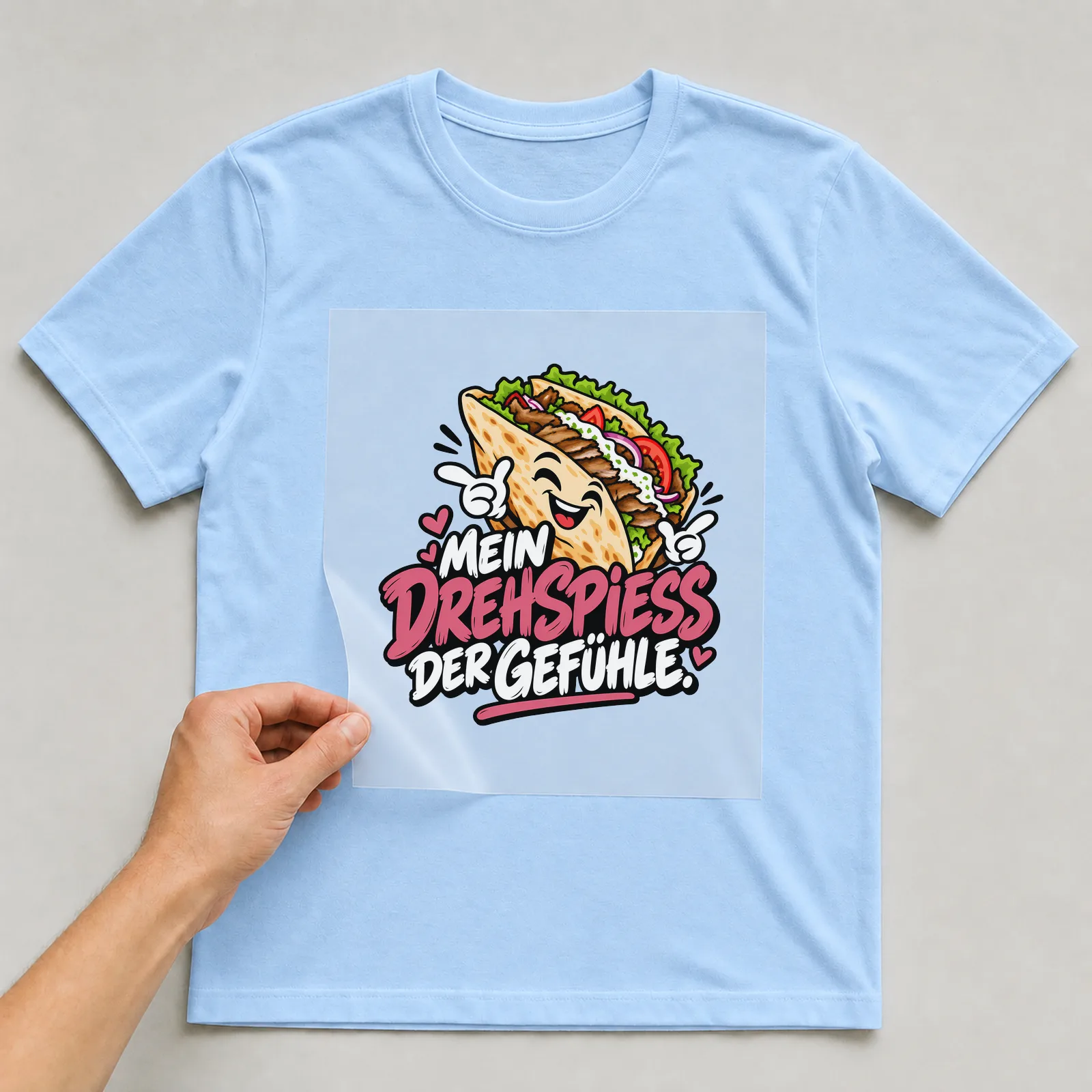 Bügelbild „Mein Drehspieß der Gefühle“ auf hellblauem T-Shirt, Folie wird aufgelegt