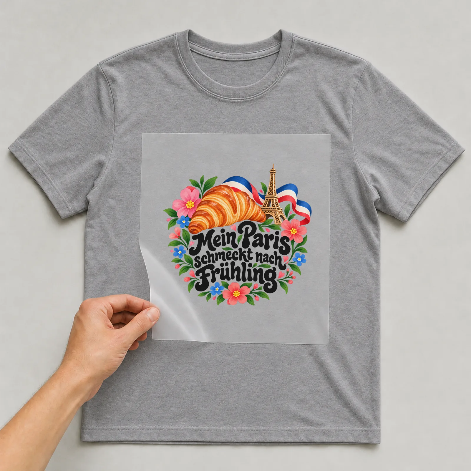 Bügelbild „Mein Paris schmeckt nach Frühling“ auf grauem T-Shirt, Folie wird aufgelegt