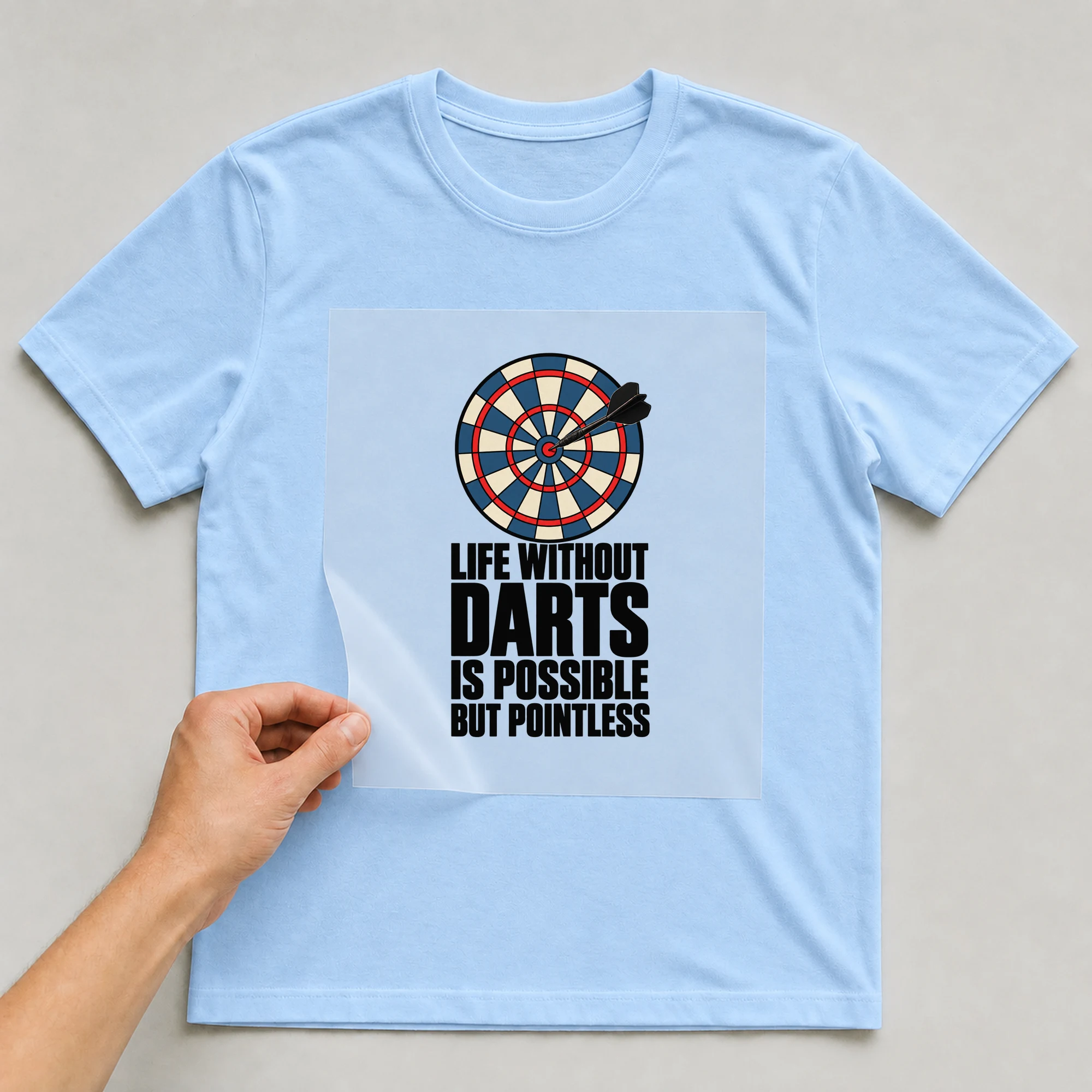 Bügelbild „Life Without Darts Is Possible But Pointless“ auf babyblauem T-Shirt, Folie wird aufgelegt