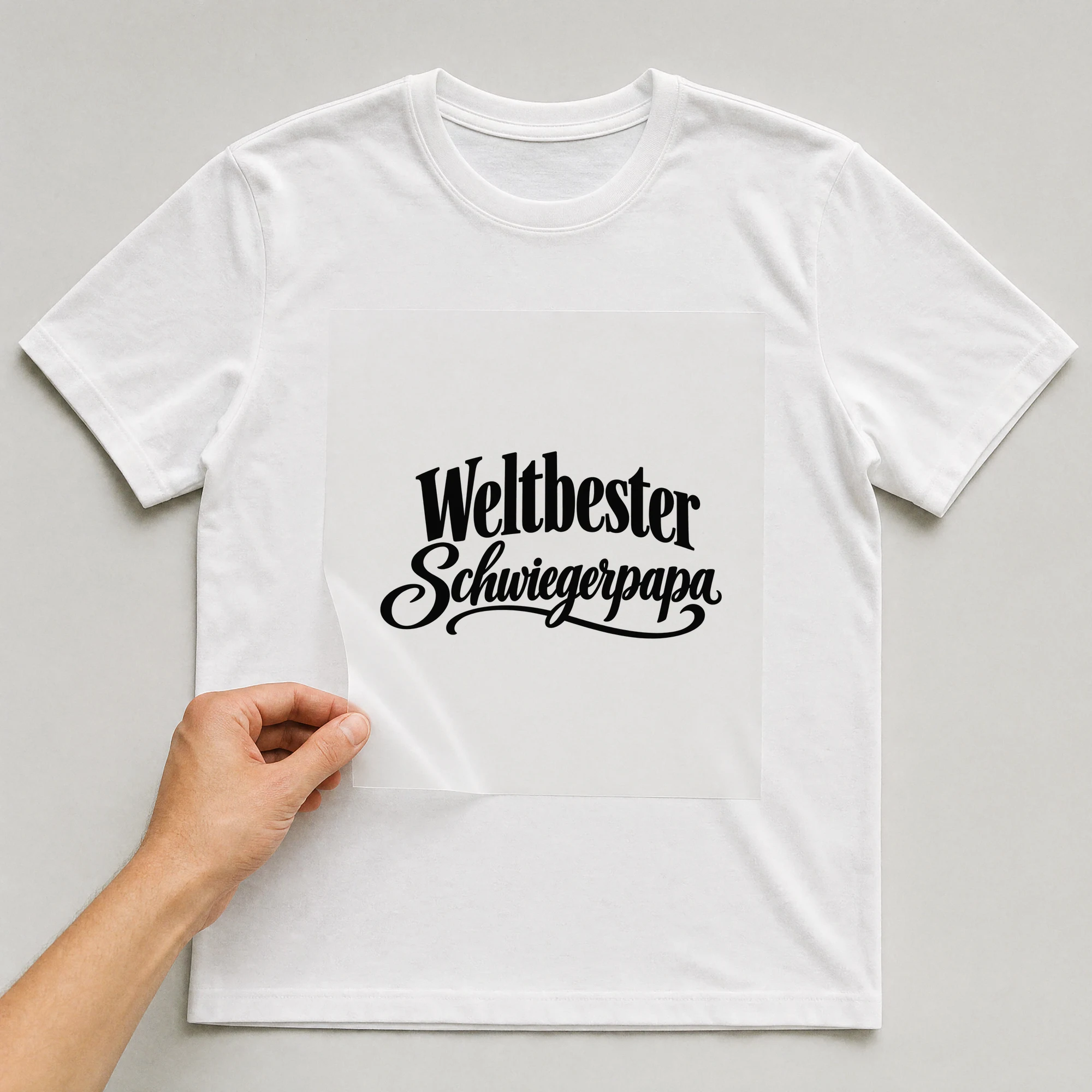 Bügelbild „Weltbester Schwiegerpapa“ auf weißem T-Shirt, Folie wird aufgelegt