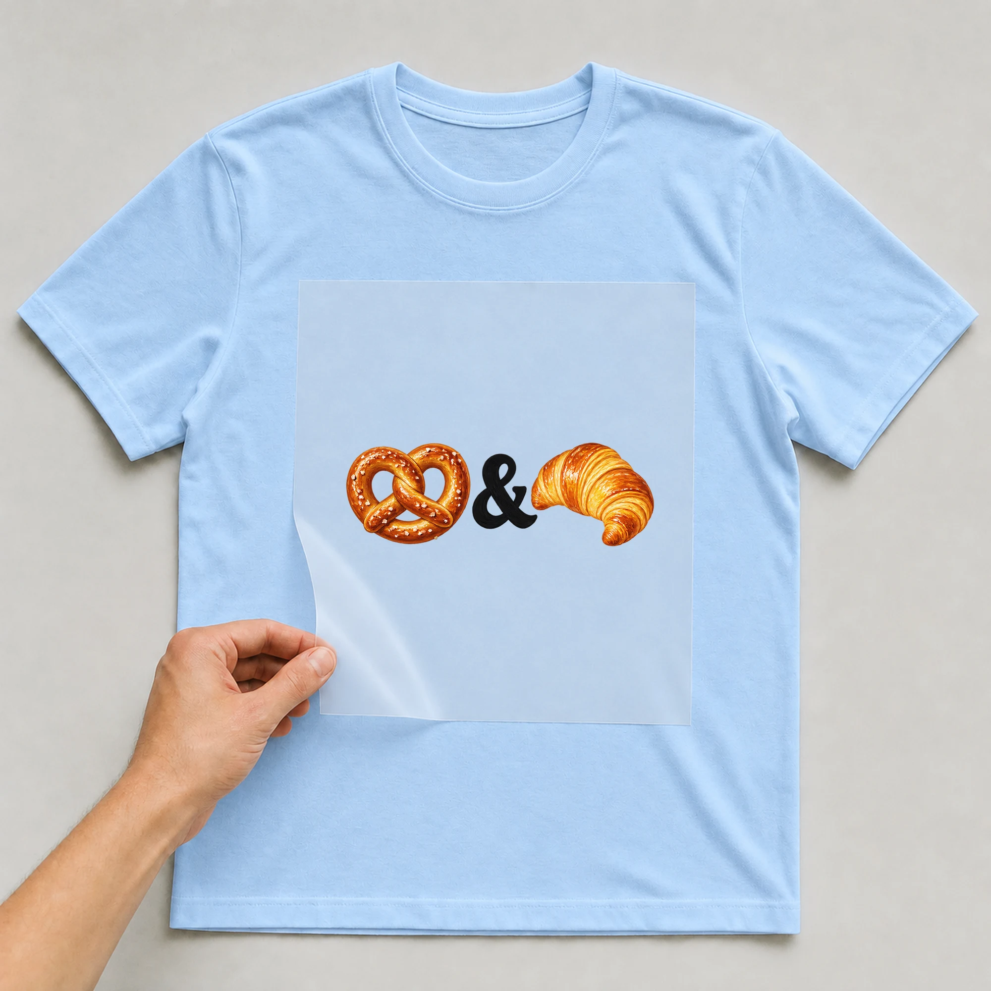 Bügelbild „&“ auf babyblauem T-Shirt, Folie wird aufgelegt