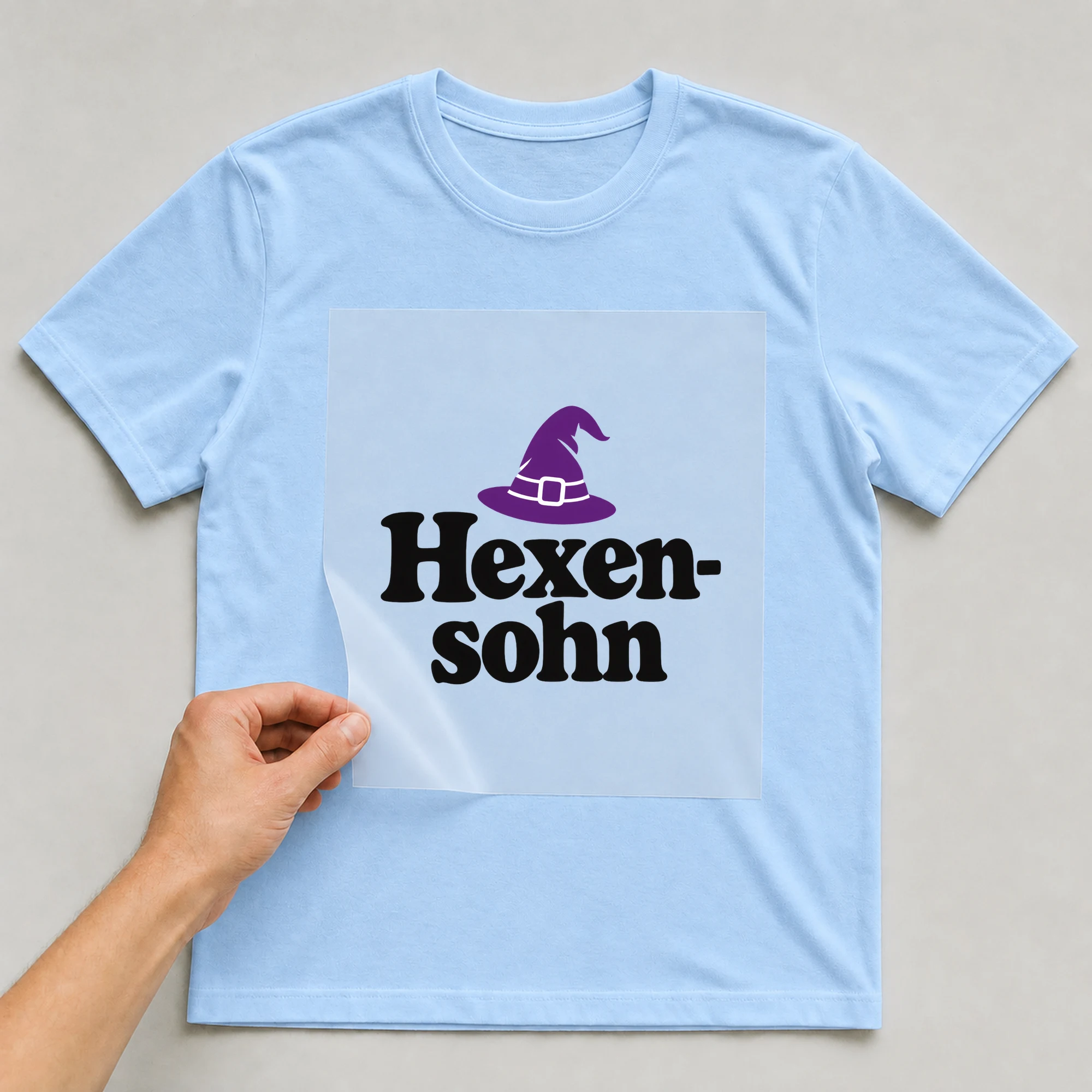 Bügelbild „Hexensohn“ auf babyblauem T-Shirt, Folie wird aufgelegt