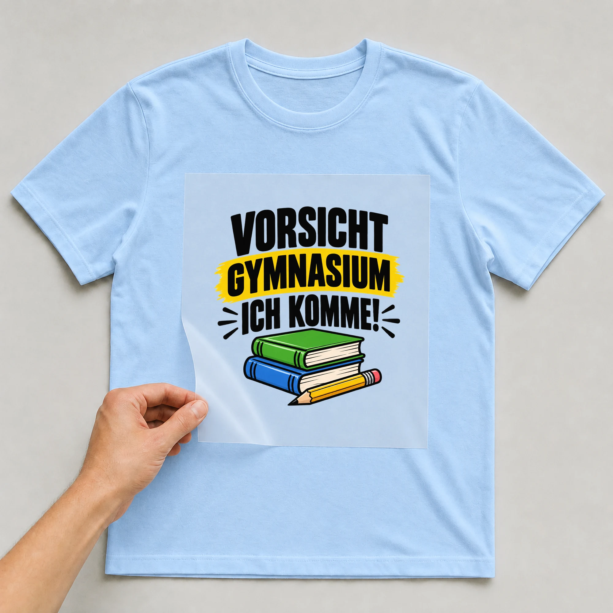 Bügelbild „Vorsicht Gymnasium, ich komme!“ auf babyblauem T-Shirt, Folie wird aufgelegt