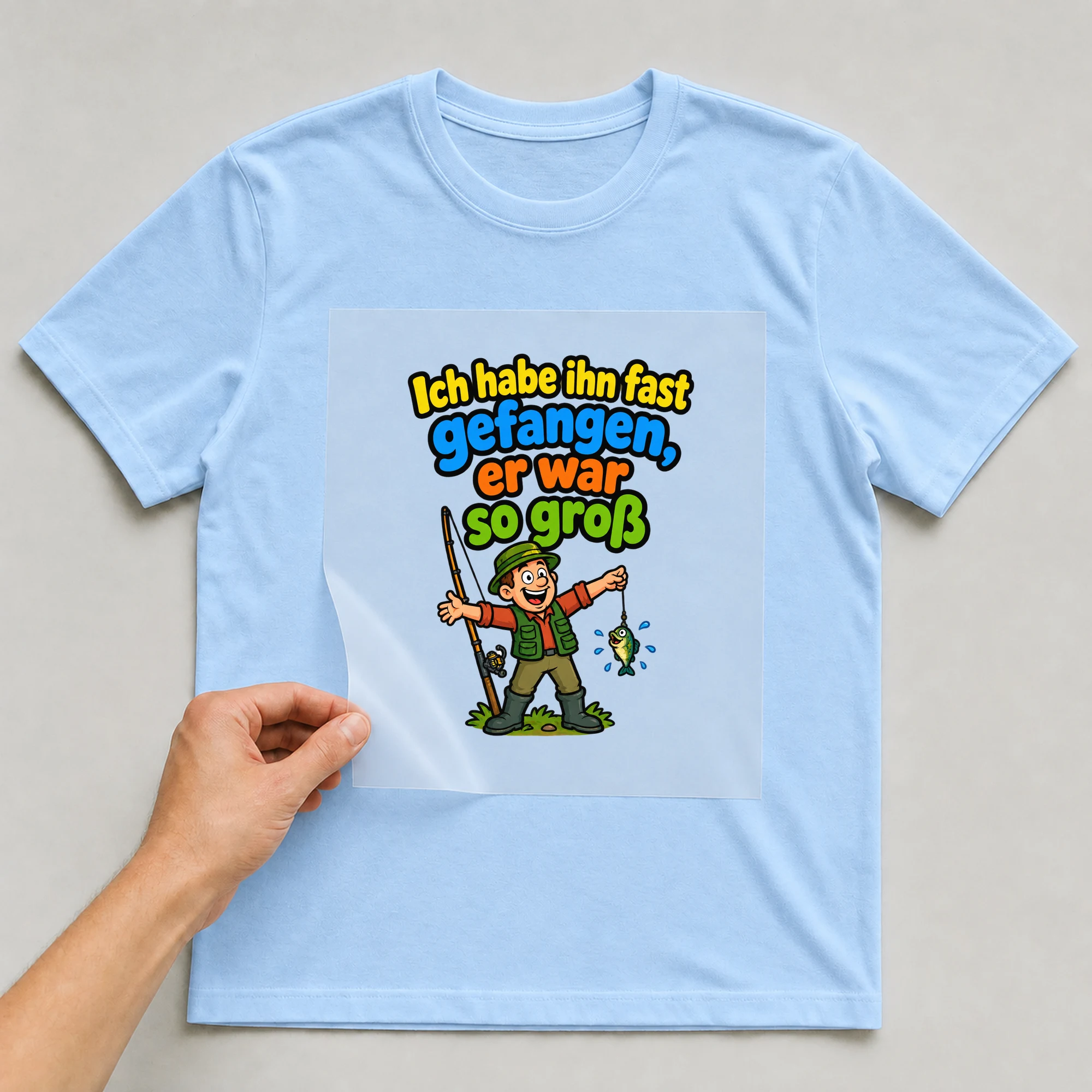 Bügelbild „Ich habe ihn fast gefangen, er war so groß“ auf babyblauem T-Shirt, Folie wird aufgelegt
