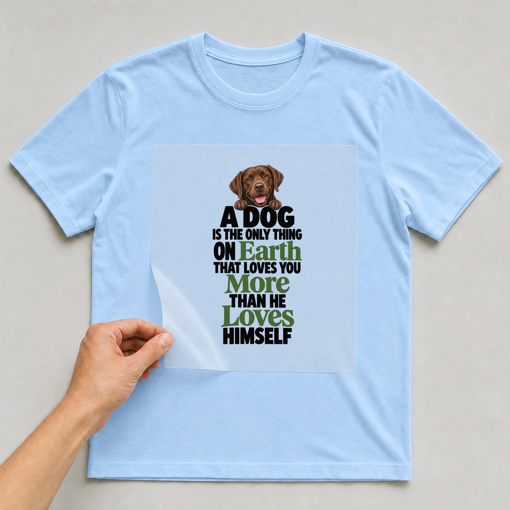 Bügelbild „A Dog Is The Only Thing On Earth That Loves You More Than He Loves Himself“ auf babyblauem T-Shirt, Folie wird aufgelegt