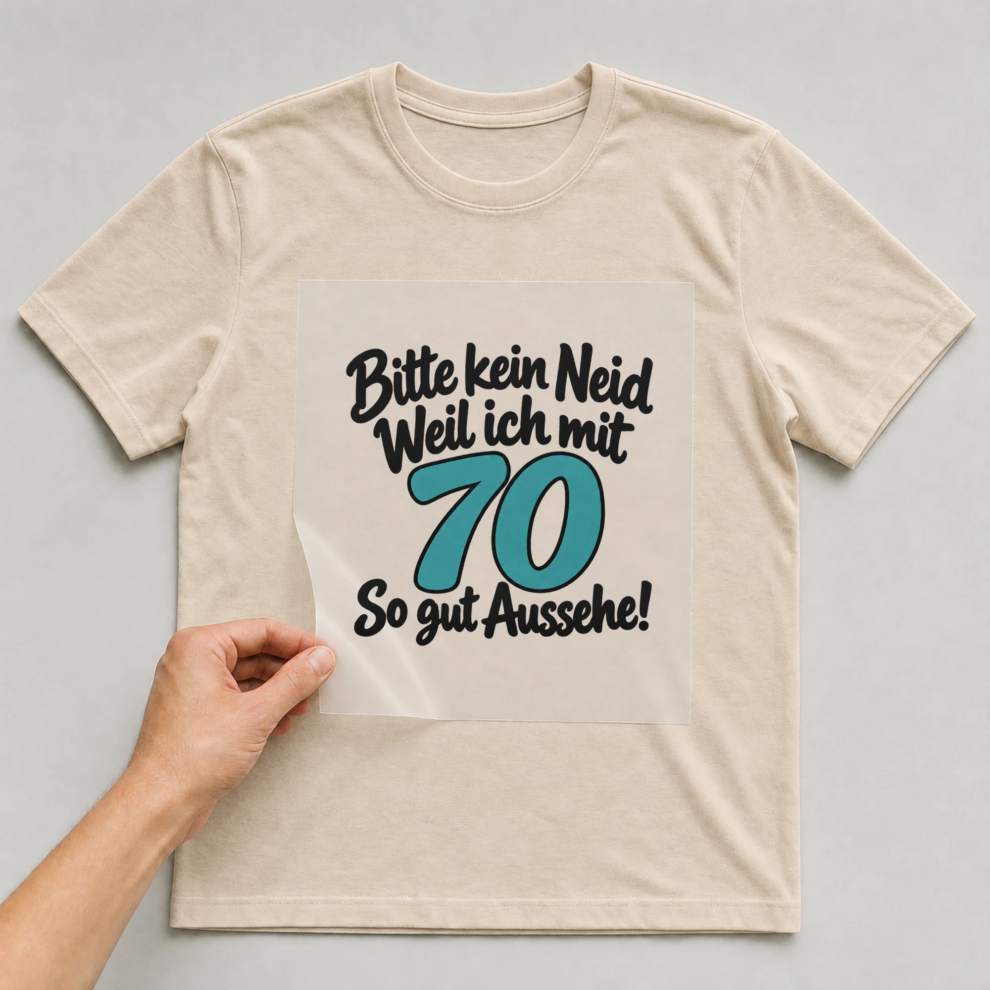 Bügelbild „Bitte kein Neid Weil ich mit 70 So gut Aussehe!“ auf beigem T-Shirt, Folie wird aufgelegt