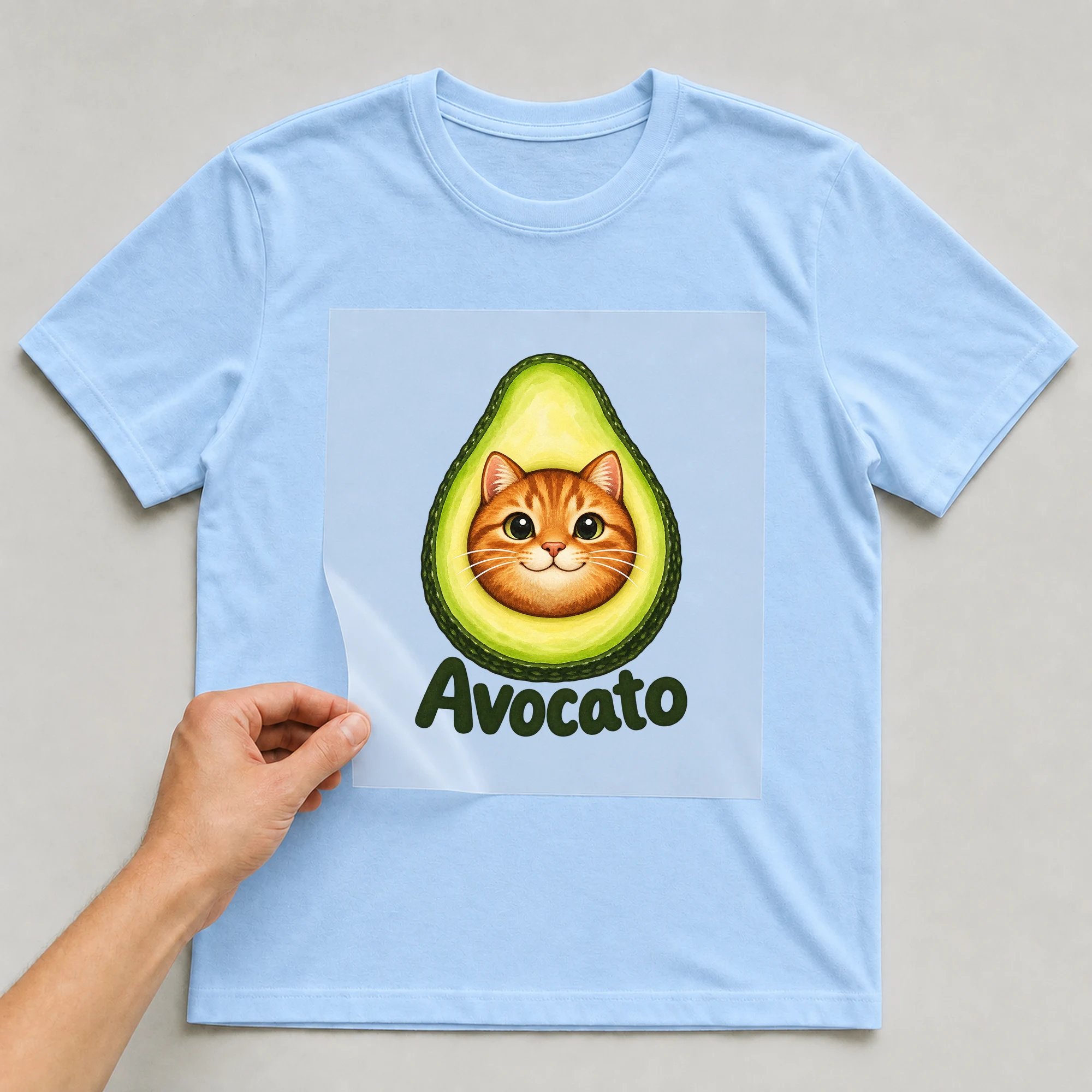Bügelbild „Avocato“ auf babyblauem T-Shirt, Folie wird aufgelegt