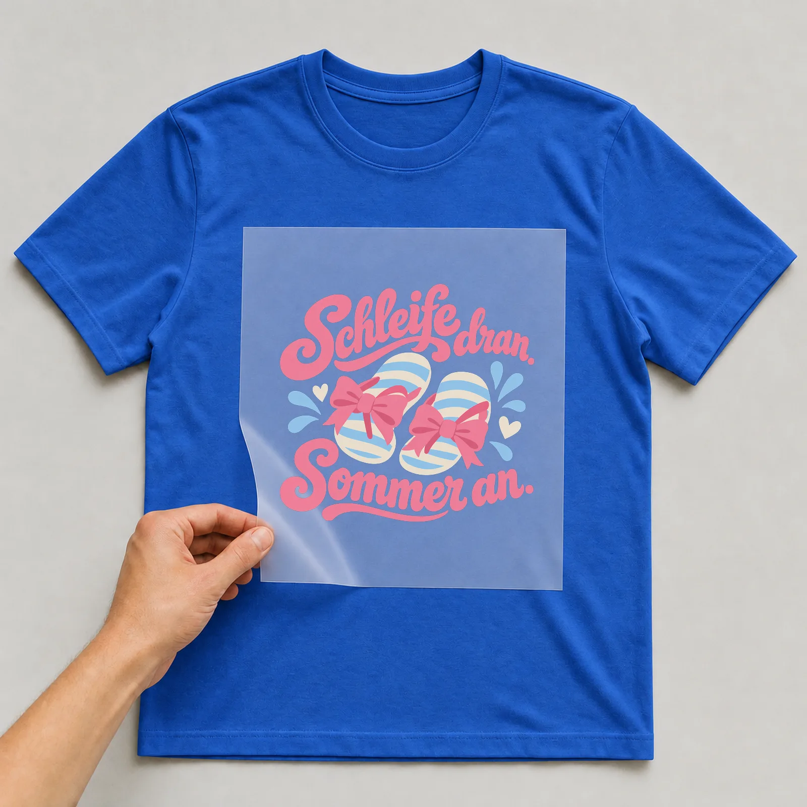 Bügelbild „Schleife dran. Sommer an.“ auf blauem T-Shirt, Folie wird aufgelegt