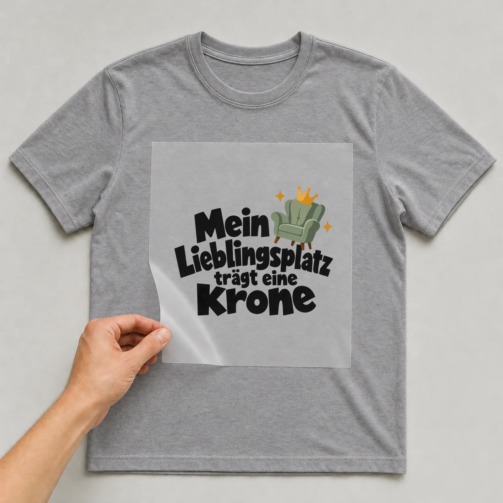 Bügelbild „Mein Lieblingsplatz trägt eine Krone“ auf grauem T-Shirt, Folie wird aufgelegt
