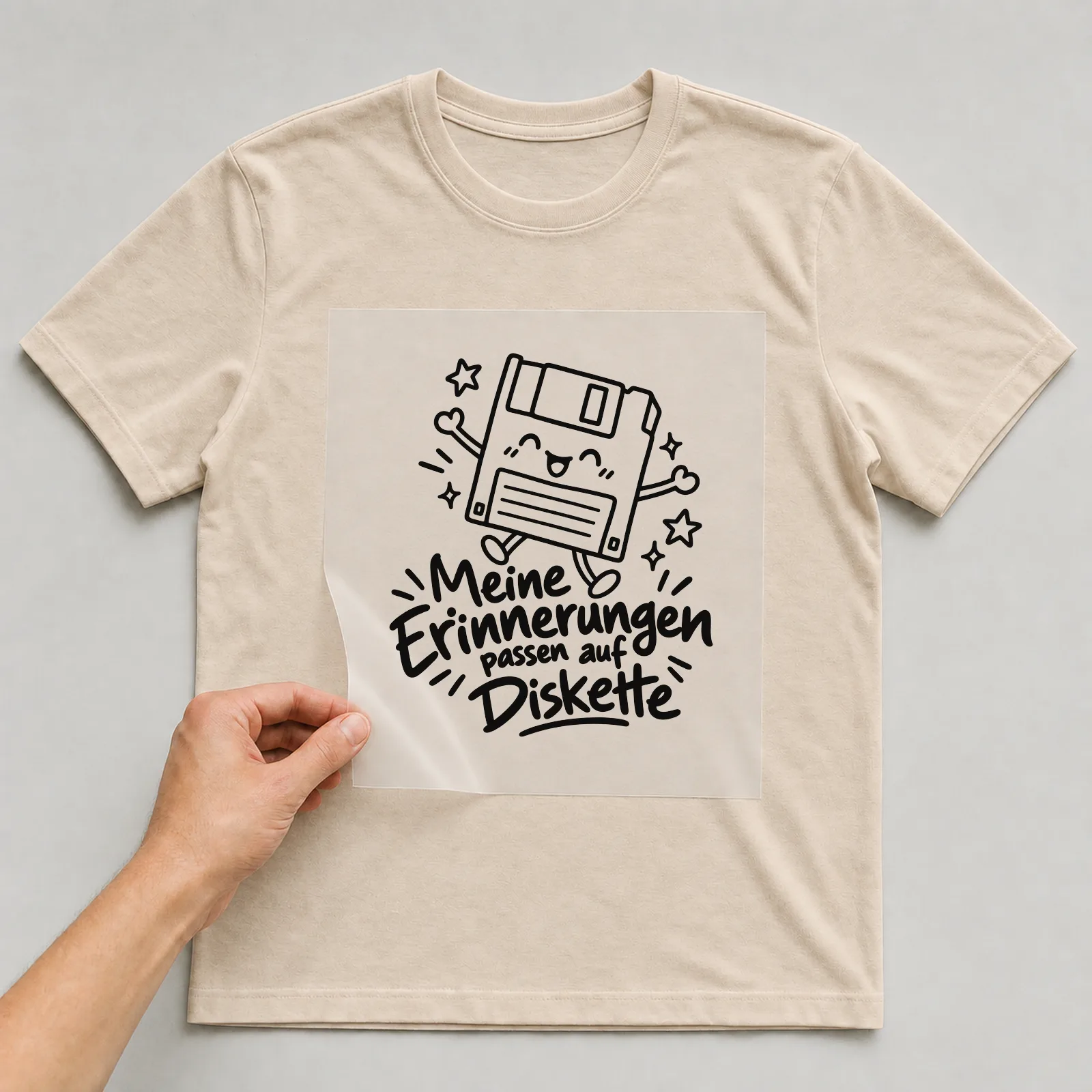 Bügelbild „Meine Erinnerungen passen auf Diskette“ auf beigem T-Shirt, Folie wird aufgelegt