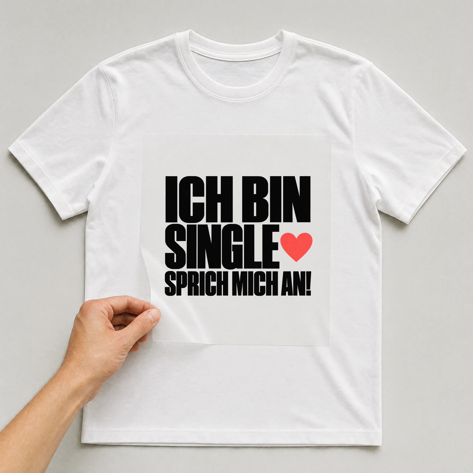 Bügelbild „Ich Bin Single Sprich Mich An!“ auf weißem T-Shirt, Folie wird aufgelegt
