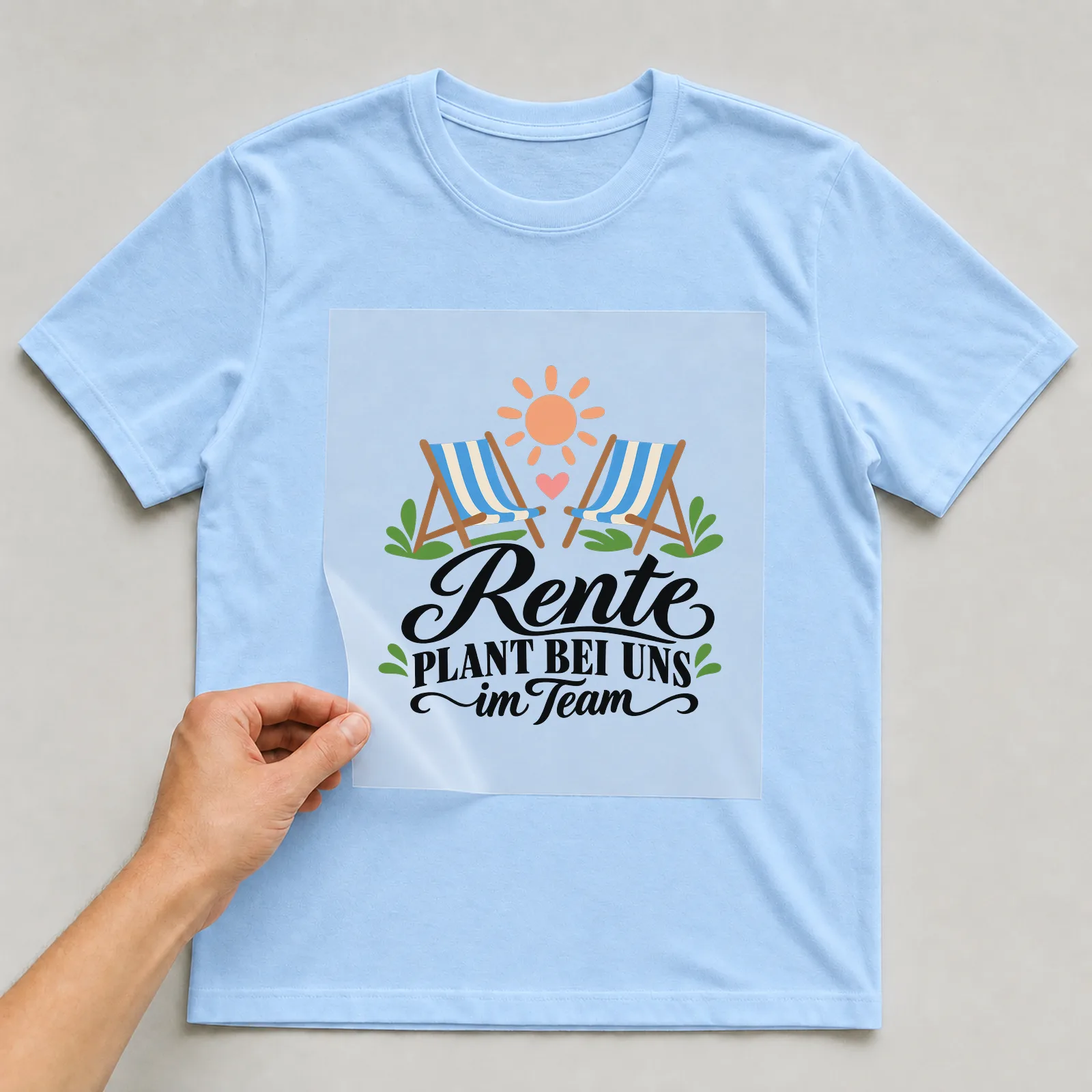 Bügelbild „Rente PLANT BEI UNS im Team“ auf hellblauem T-Shirt, Folie wird aufgelegt