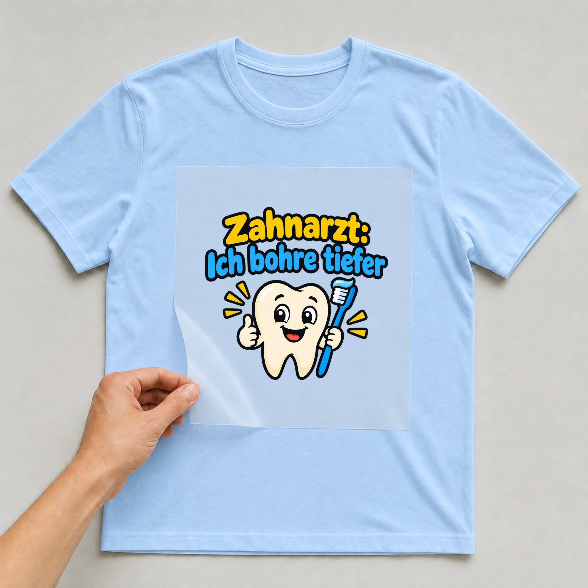 Bügelbild „Zahnarzt: Ich bohre tiefer“ auf babyblauem T-Shirt, Folie wird aufgelegt