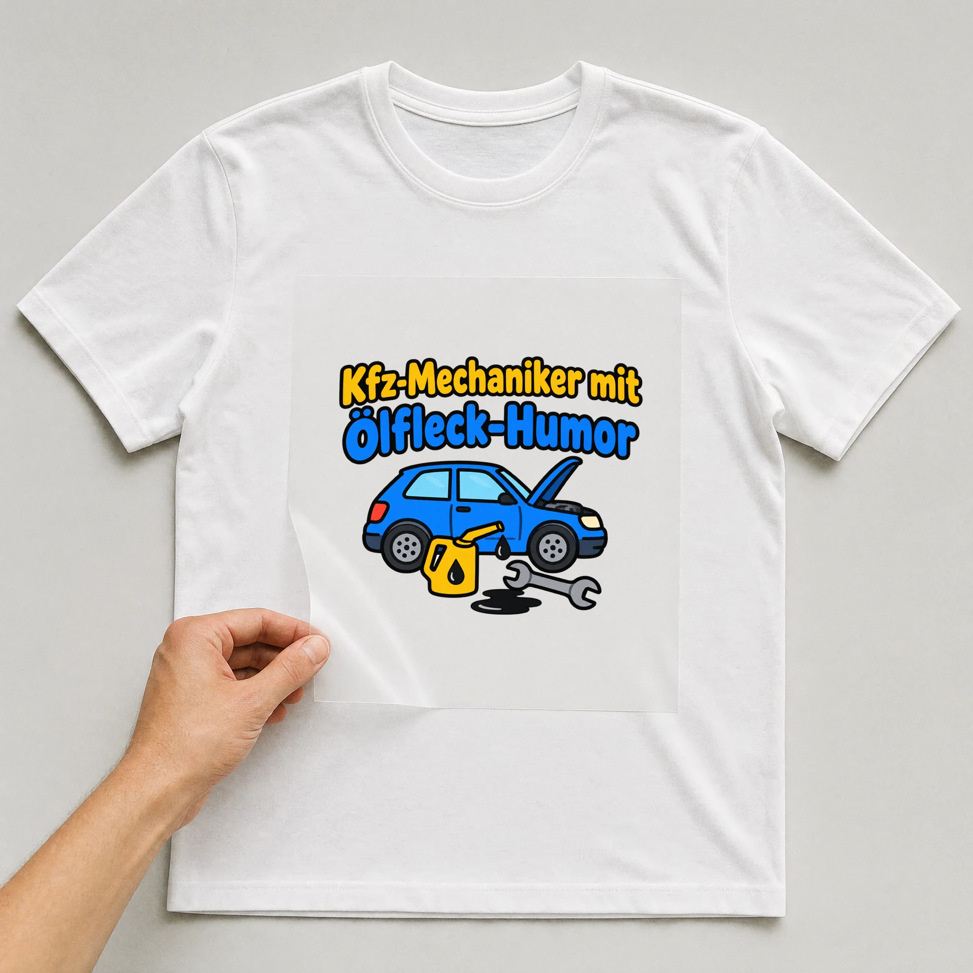Bügelbild „Kfz-Mechaniker mit Ölfleck-Humor“ auf weißem T-Shirt, Folie wird aufgelegt