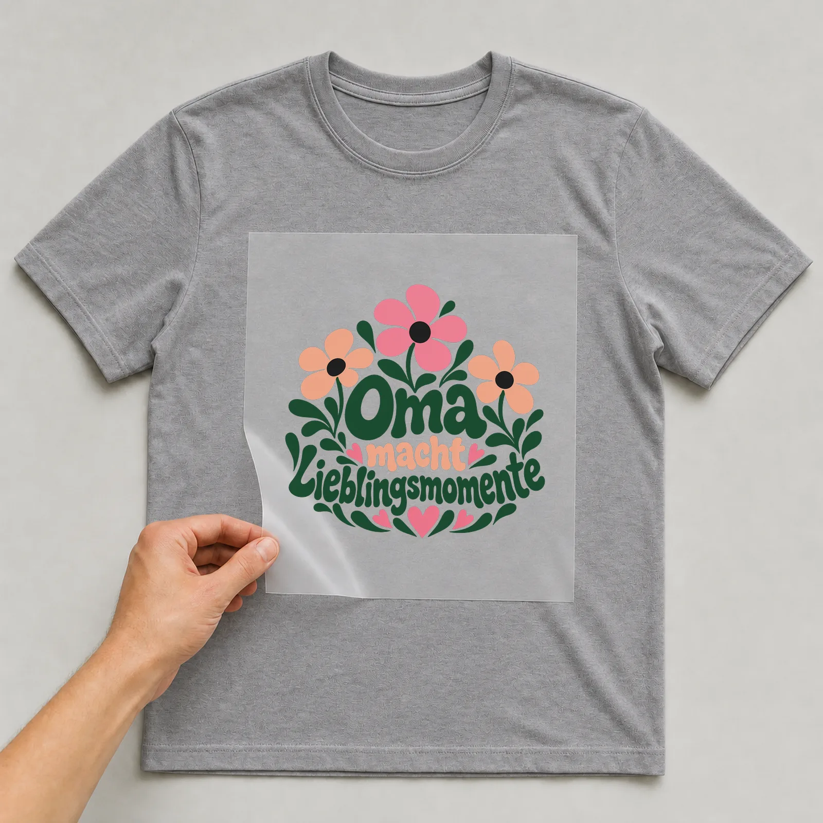 Bügelbild „Oma macht Lieblingsmomente“ auf grauem T-Shirt, Folie wird aufgelegt
