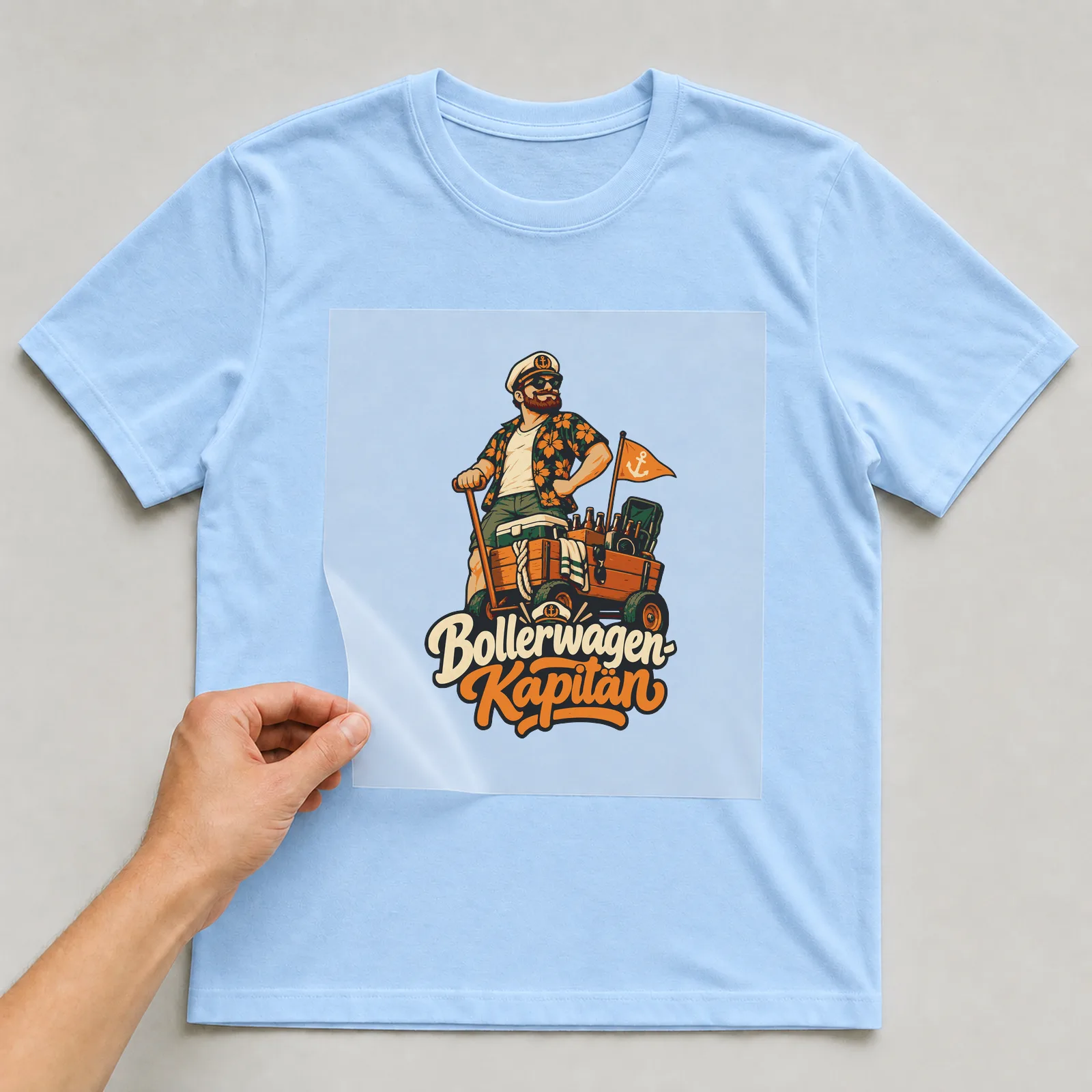 Bügelbild Bollerwagen-Kapitän auf hellblauem T-Shirt, Folie wird aufgelegt