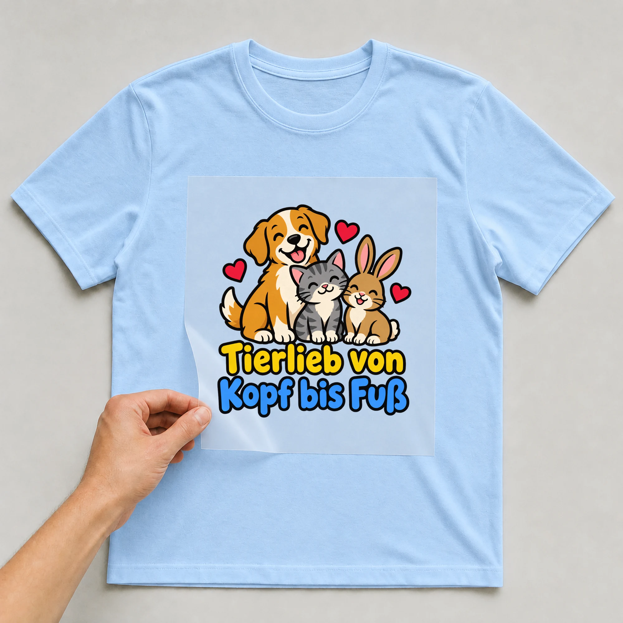 Bügelbild „Tierlieb von Kopf bis Fuß“ auf babyblauem T-Shirt, Folie wird aufgelegt