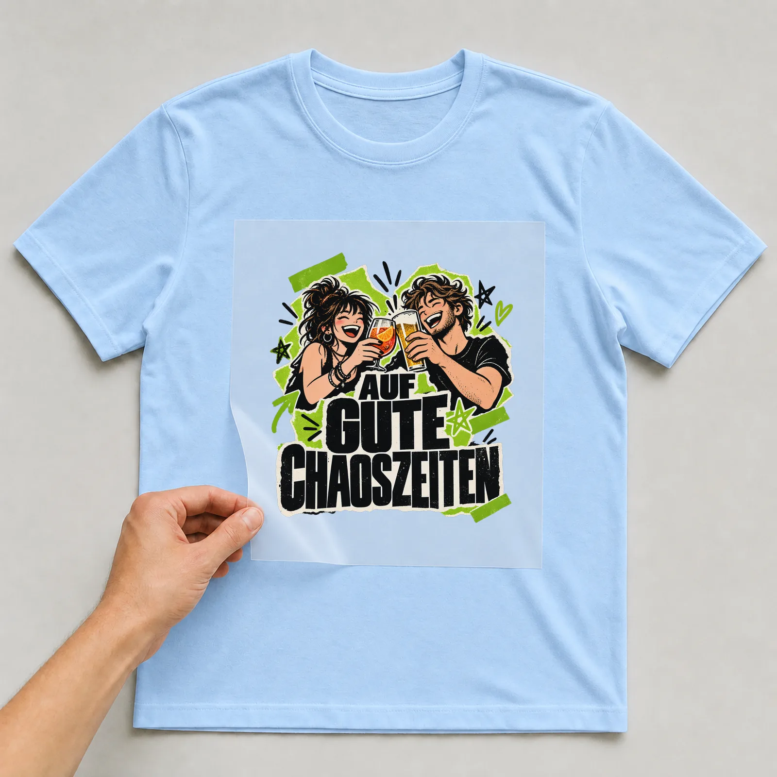 Bügelbild „Auf gute Chaoszeiten“ auf hellblauem T-Shirt, Folie wird aufgelegt