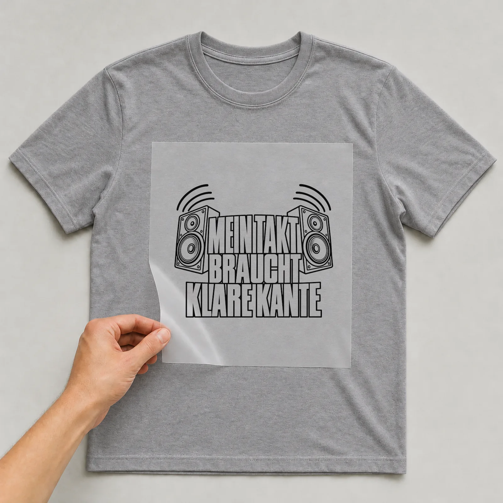 Bügelbild „Mein Takt braucht klare kante“ auf grauem T-Shirt, Folie wird aufgelegt