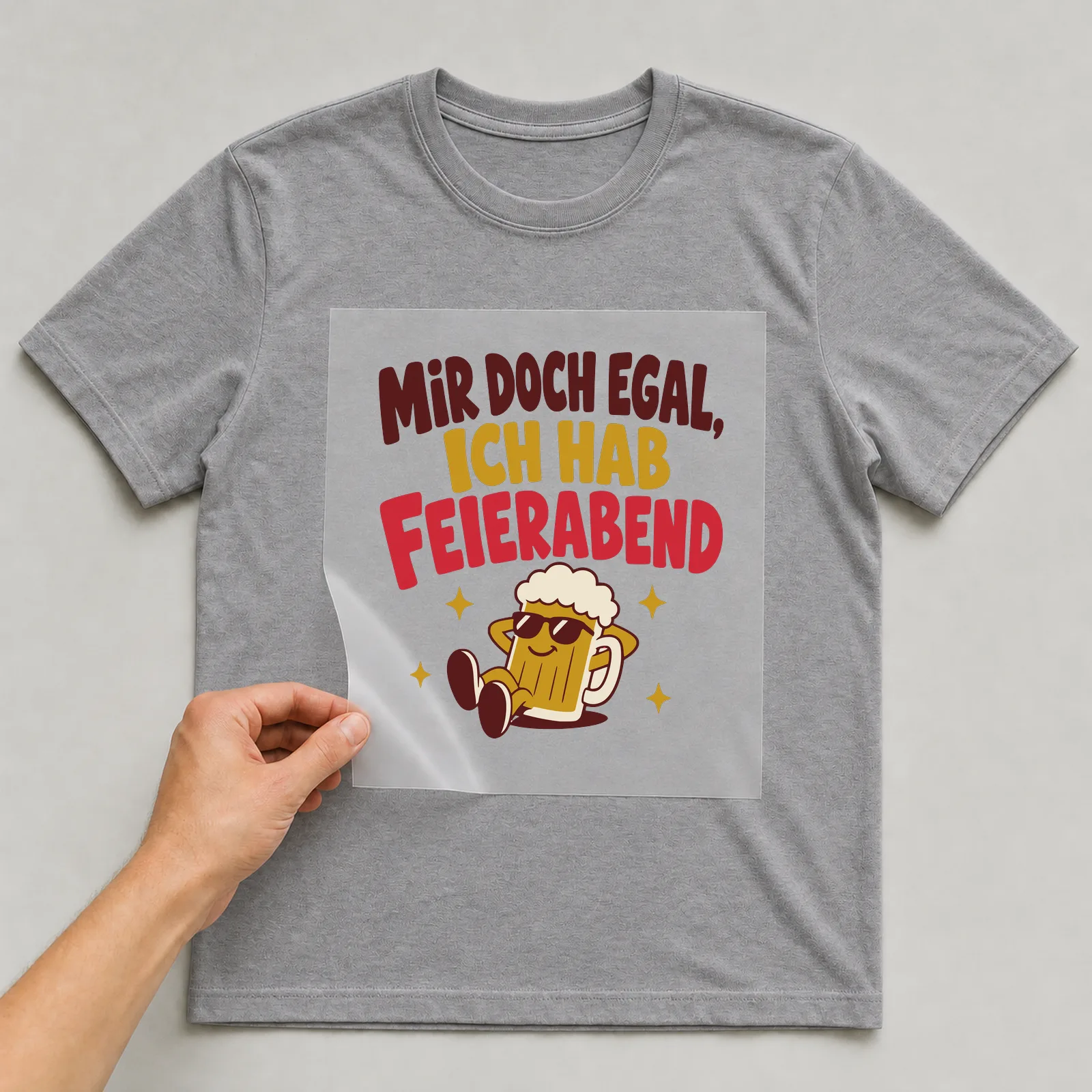 Bügelbild Mir doch egal, ich hab Feierabend auf grauem T-Shirt, Folie wird aufgelegt