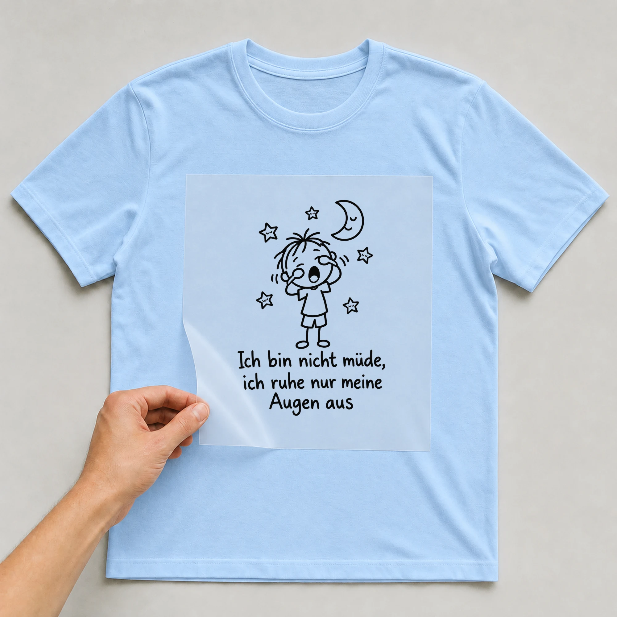 Bügelbild „Ich bin nicht müde, ich ruhe nur meine Augen aus“ auf babyblauem T-Shirt, Folie wird aufgelegt