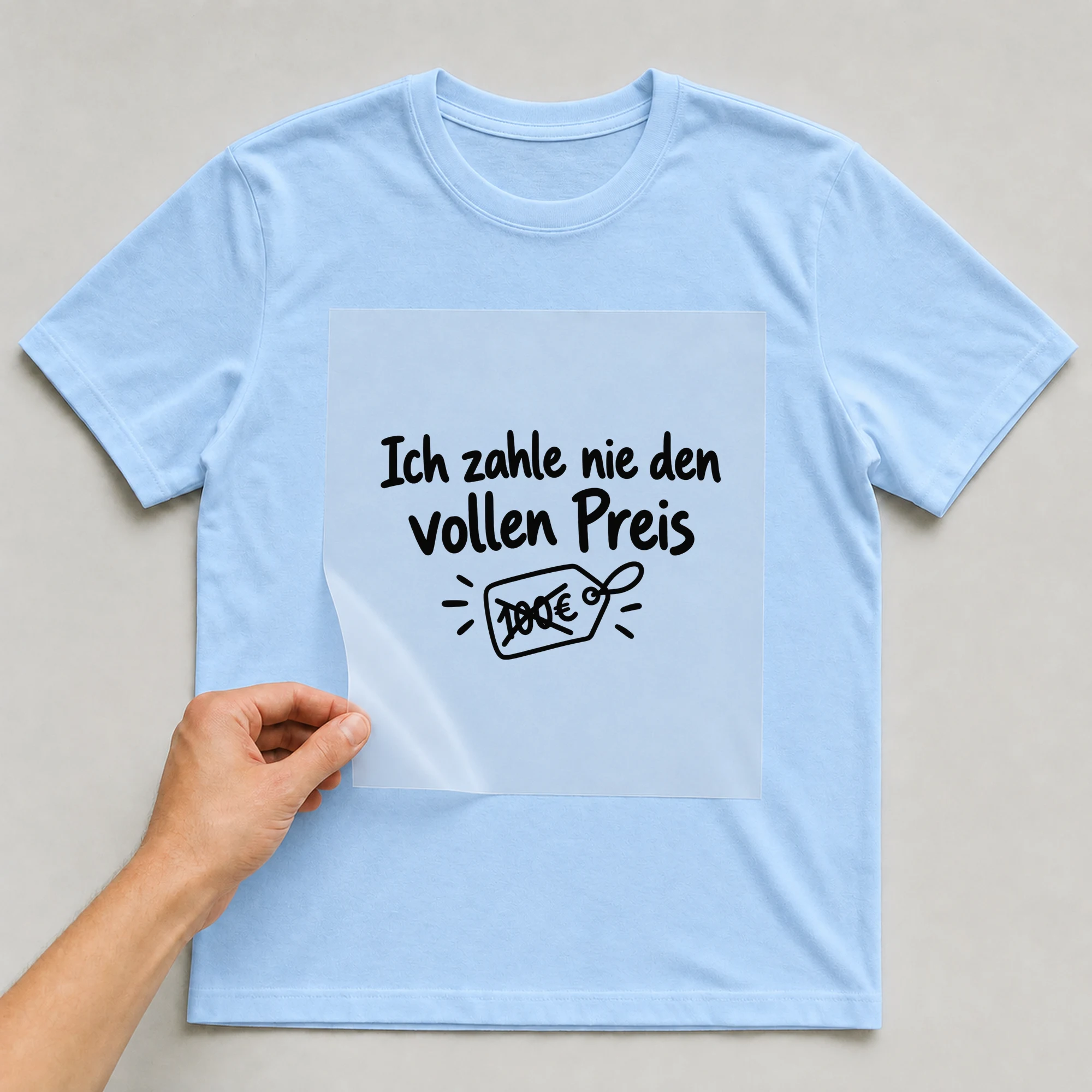 Bügelbild „Ich zahle nie den vollen Preis“ auf babyblauem T-Shirt, Folie wird aufgelegt
