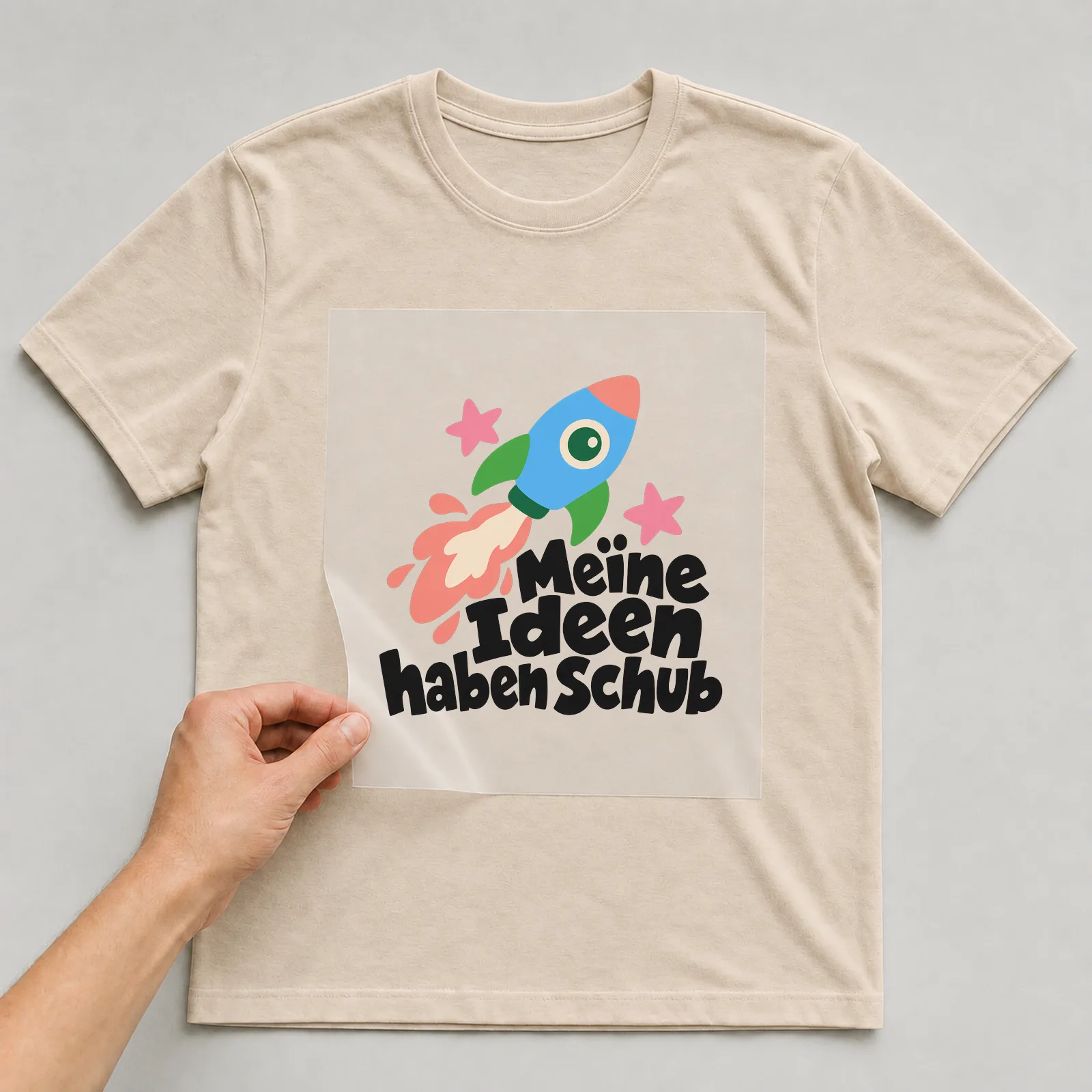 Bügelbild „Meine Ideen haben Schub“ auf beigem T-Shirt, Folie wird aufgelegt