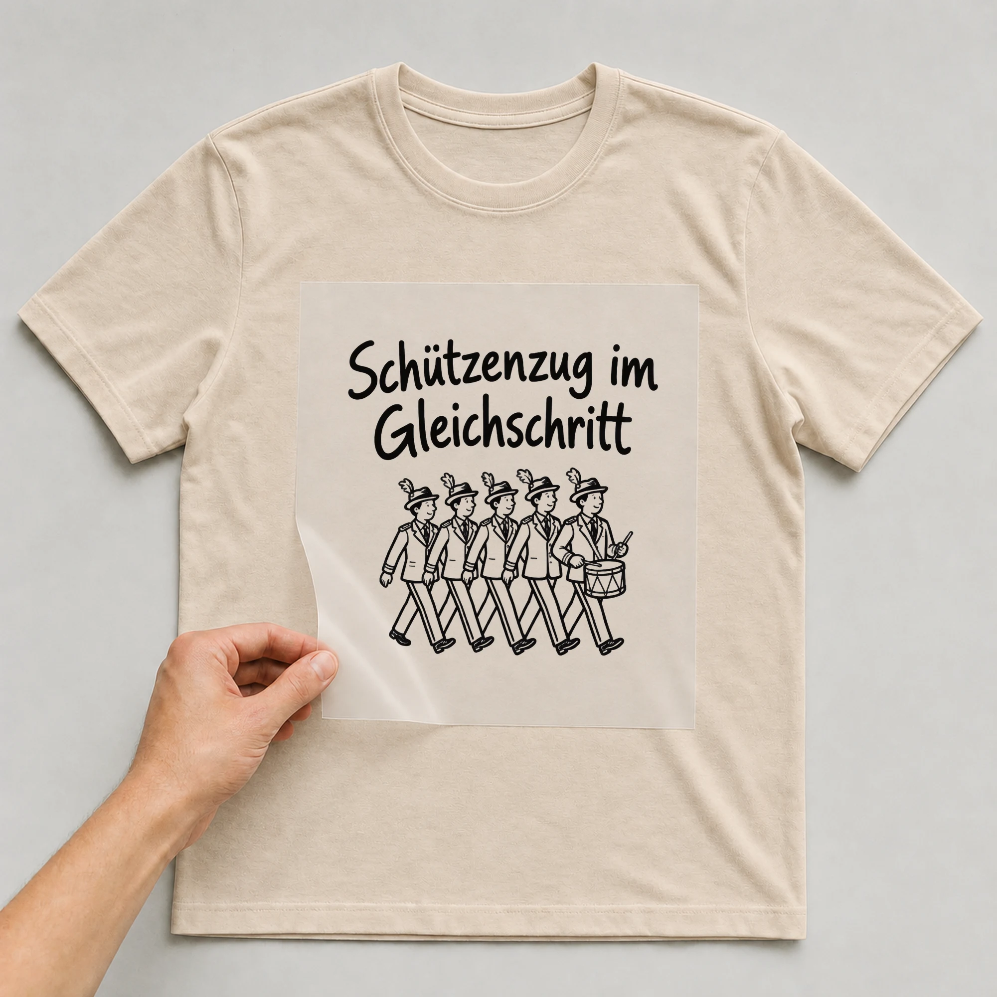 Bügelbild „Schützenzug im Gleichschritt“ auf beigem T-Shirt, Folie wird aufgelegt