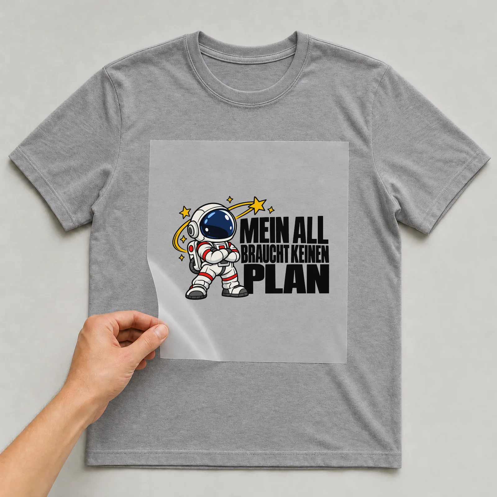 Bügelbild „Mein all braucht keinen Plan“ auf grauem T-Shirt, Folie wird aufgelegt
