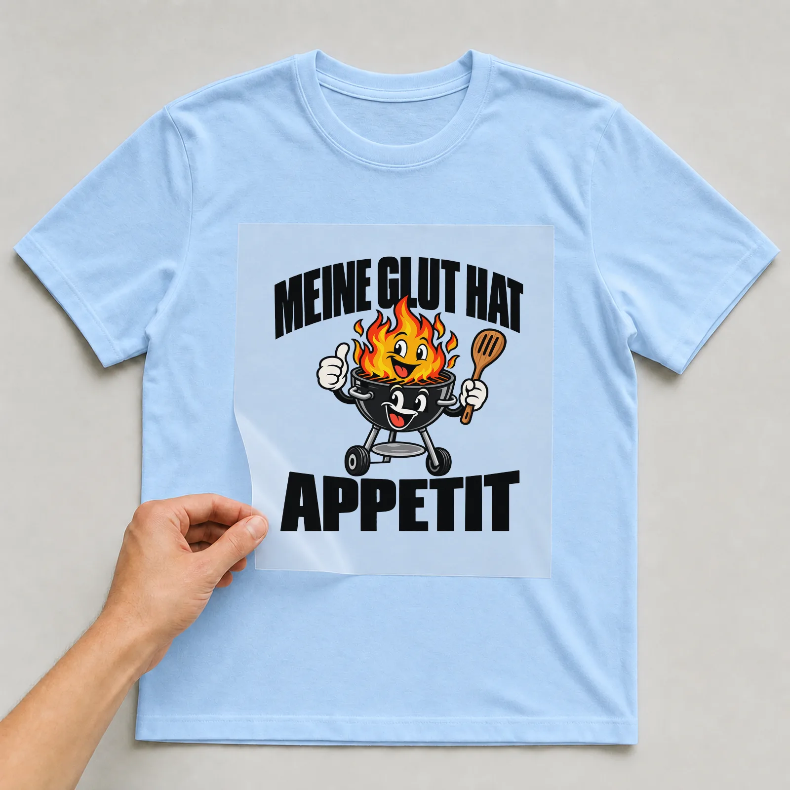 Bügelbild „Meine Glut hat Appetit“ auf hellblauem T-Shirt, Folie wird aufgelegt