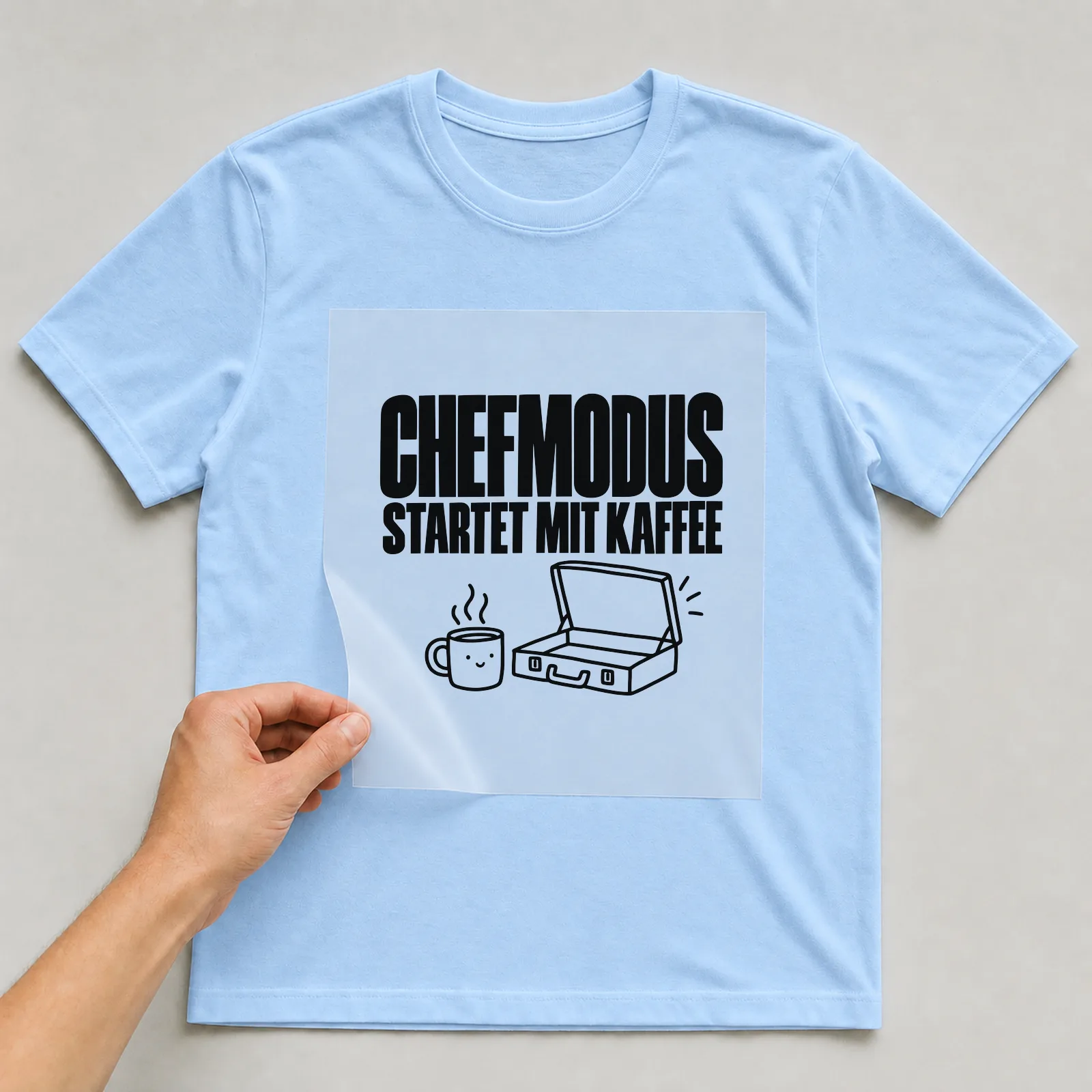 Bügelbild „Chefmodus startet mit Kaffee“ auf hellblauem T-Shirt, Folie wird aufgelegt