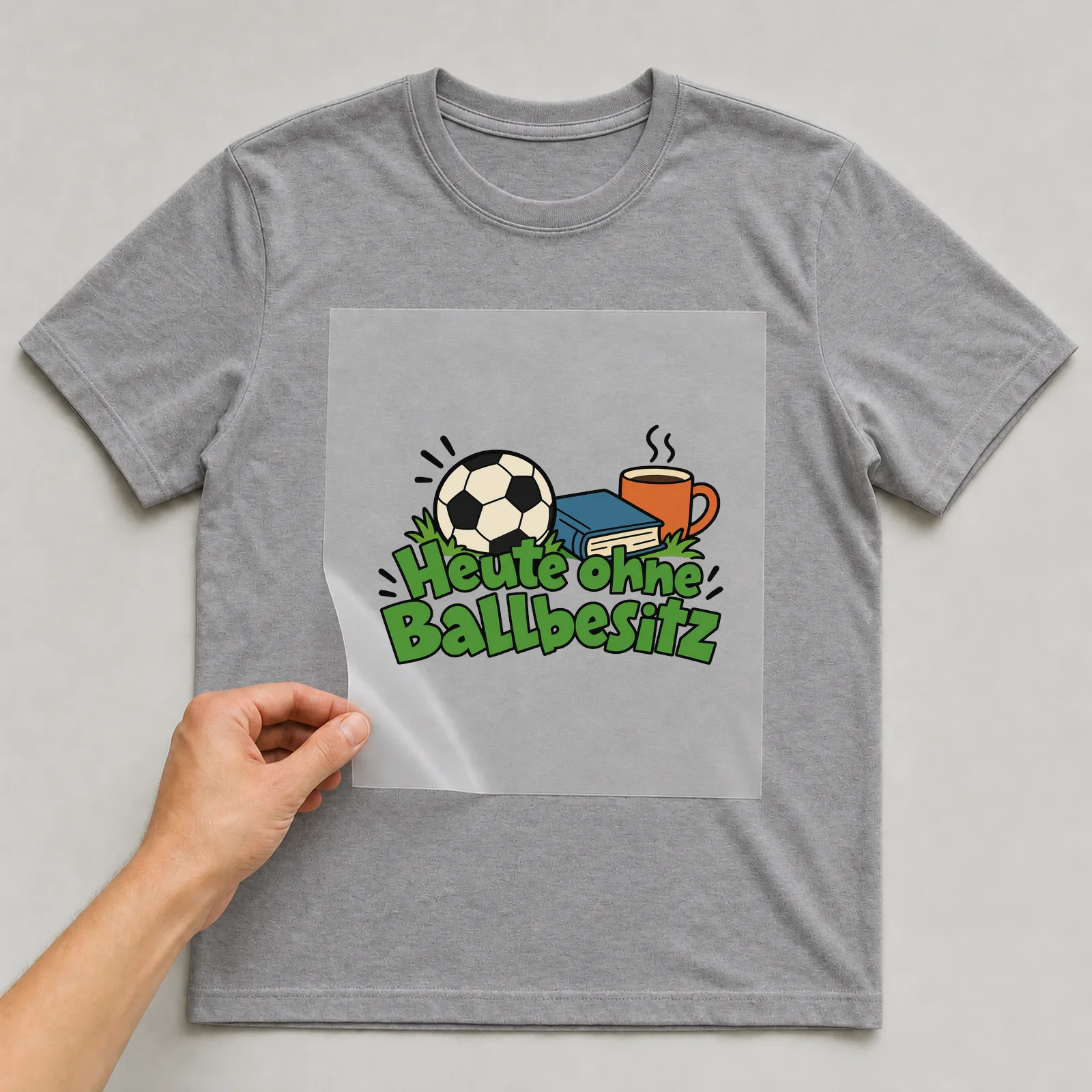 Bügelbild „Heute ohne Ballbesitz“ auf grauem T-Shirt, Folie wird aufgelegt