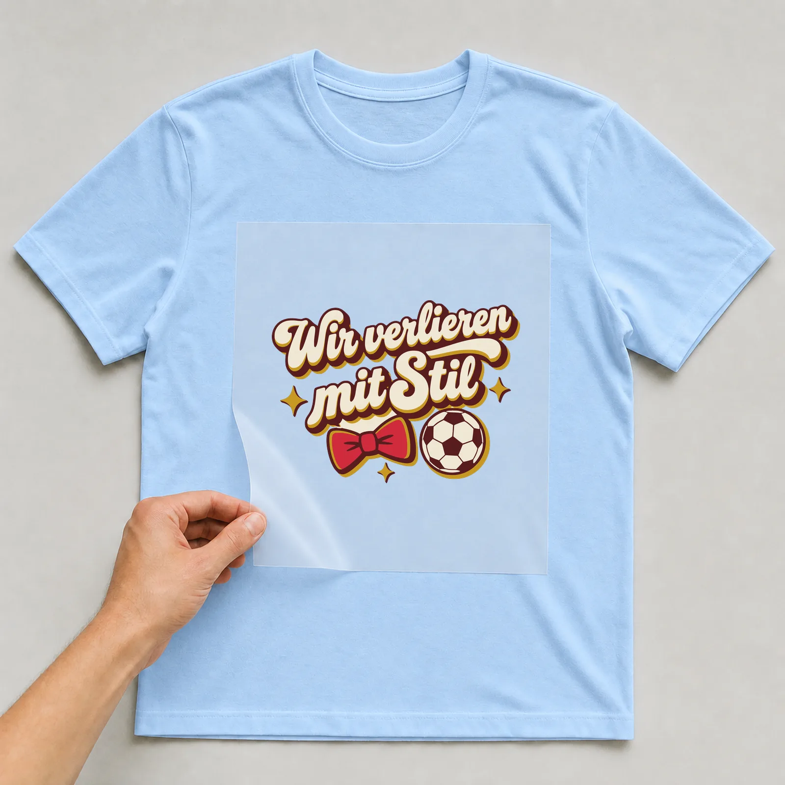 Bügelbild Wir verlieren mit Stil auf hellblauem T-Shirt, Folie wird aufgelegt
