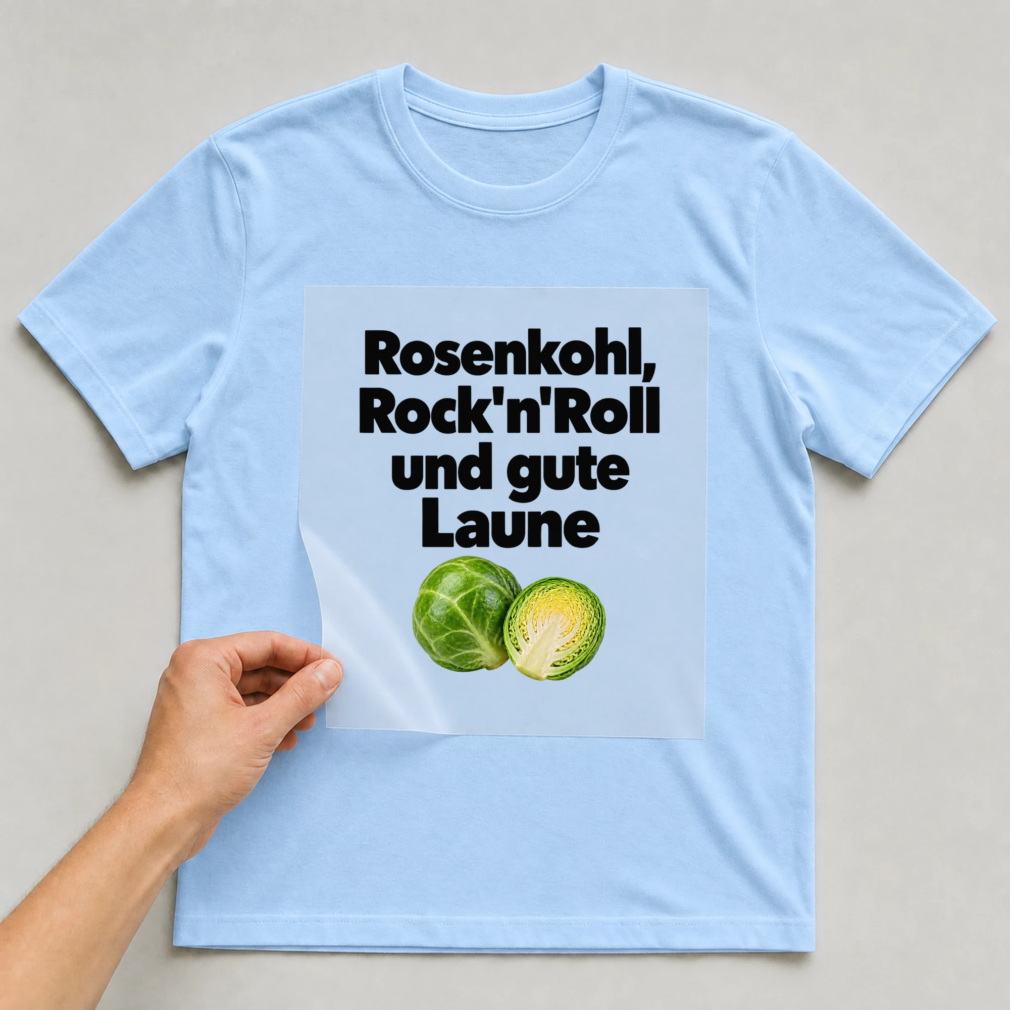 Bügelbild „Rosenkohl, Rock'n'Roll und gute Laune“ auf babyblauem T-Shirt, Folie wird aufgelegt