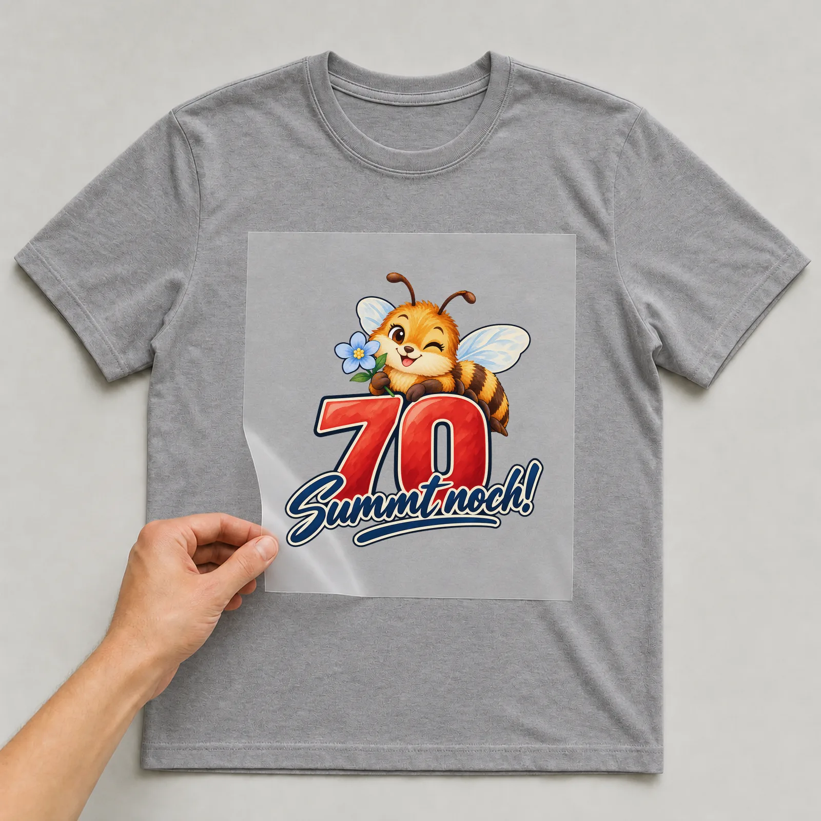 Bügelbild „70 Summt noch!“ auf grauem T-Shirt, Folie wird aufgelegt