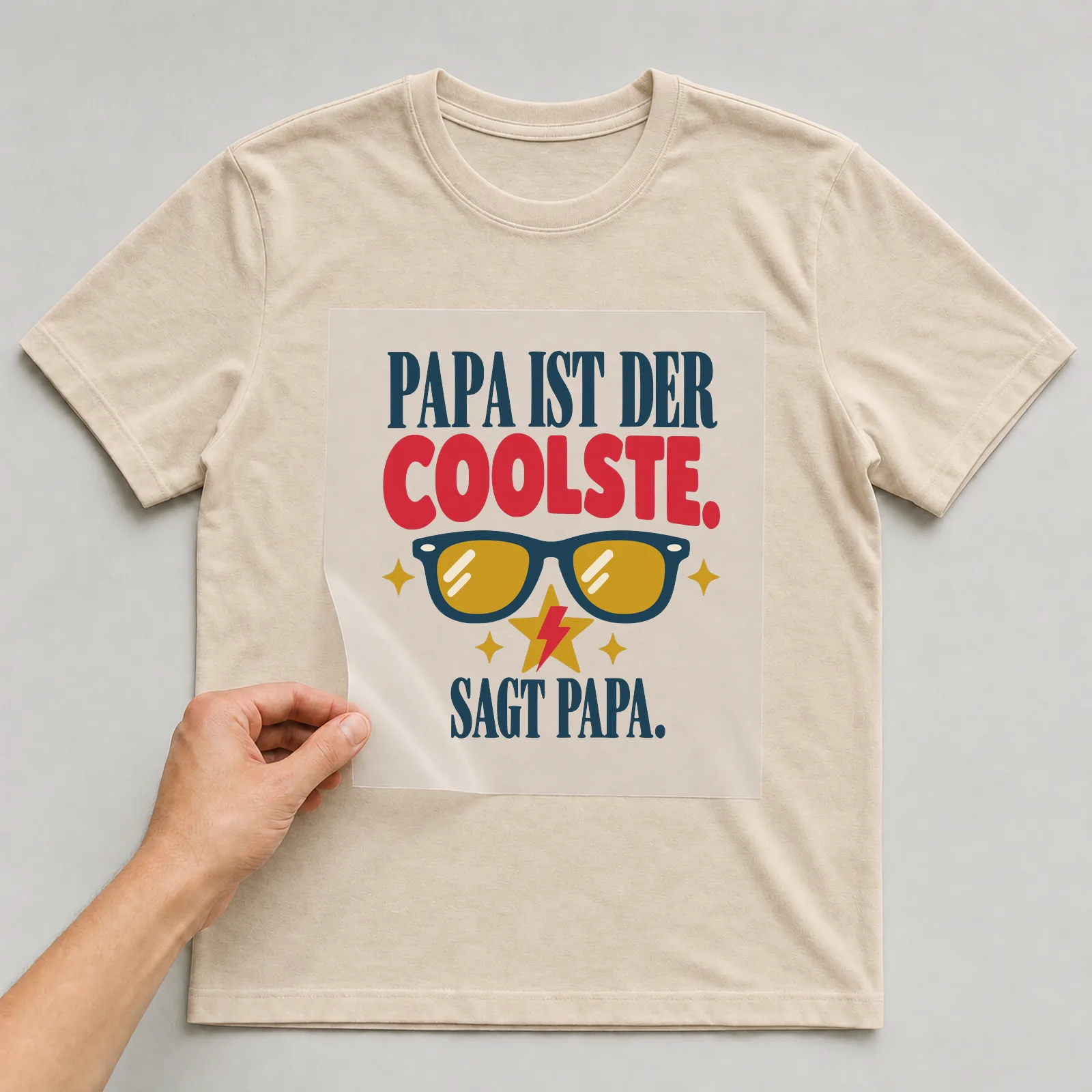 Bügelbild Papa ist der Coolste. Sagt Papa. auf beigem T-Shirt, Folie wird aufgelegt