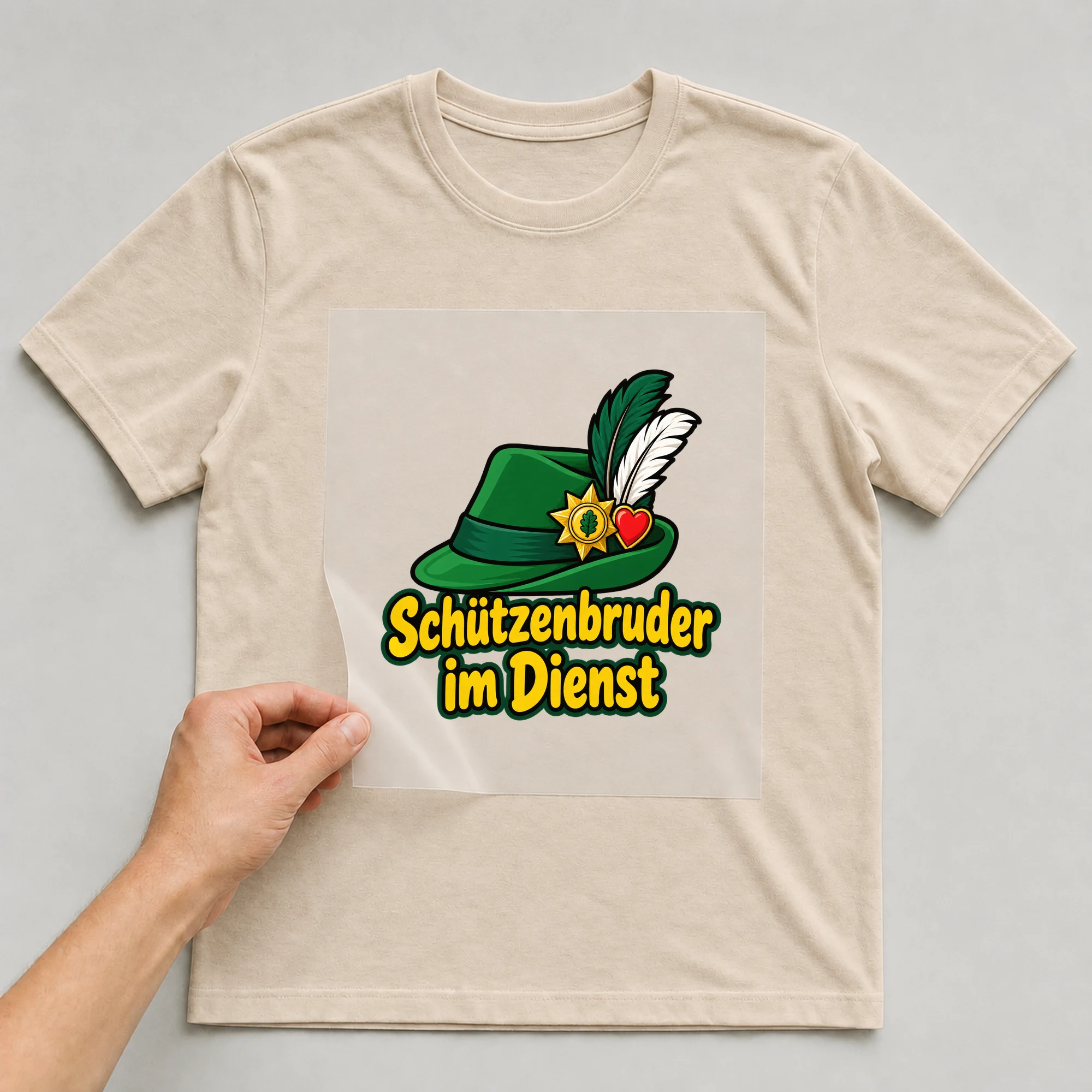 Bügelbild „Schützenbruder im Dienst“ auf beigem T-Shirt, Folie wird aufgelegt