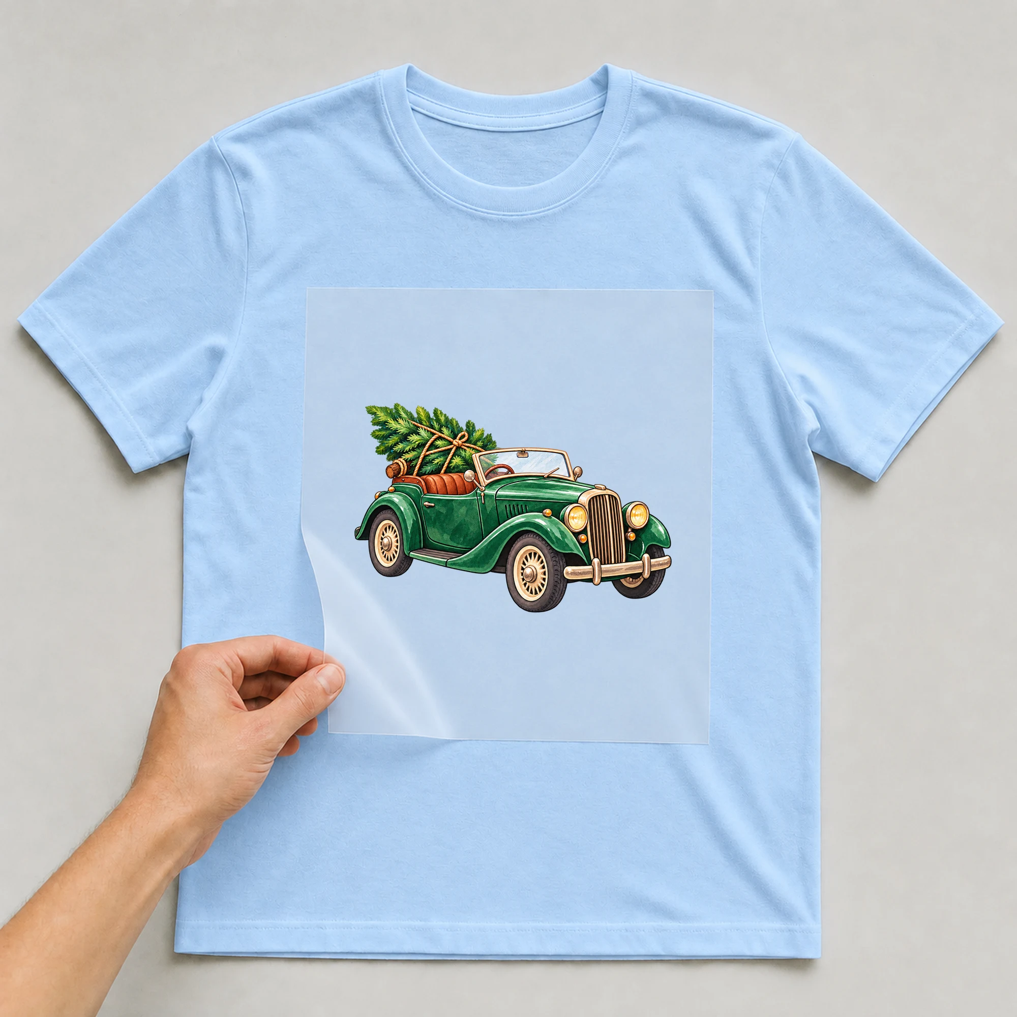 Bügelbild „Weihnachten Oldtimer“ auf babyblauem T-Shirt, Folie wird aufgelegt