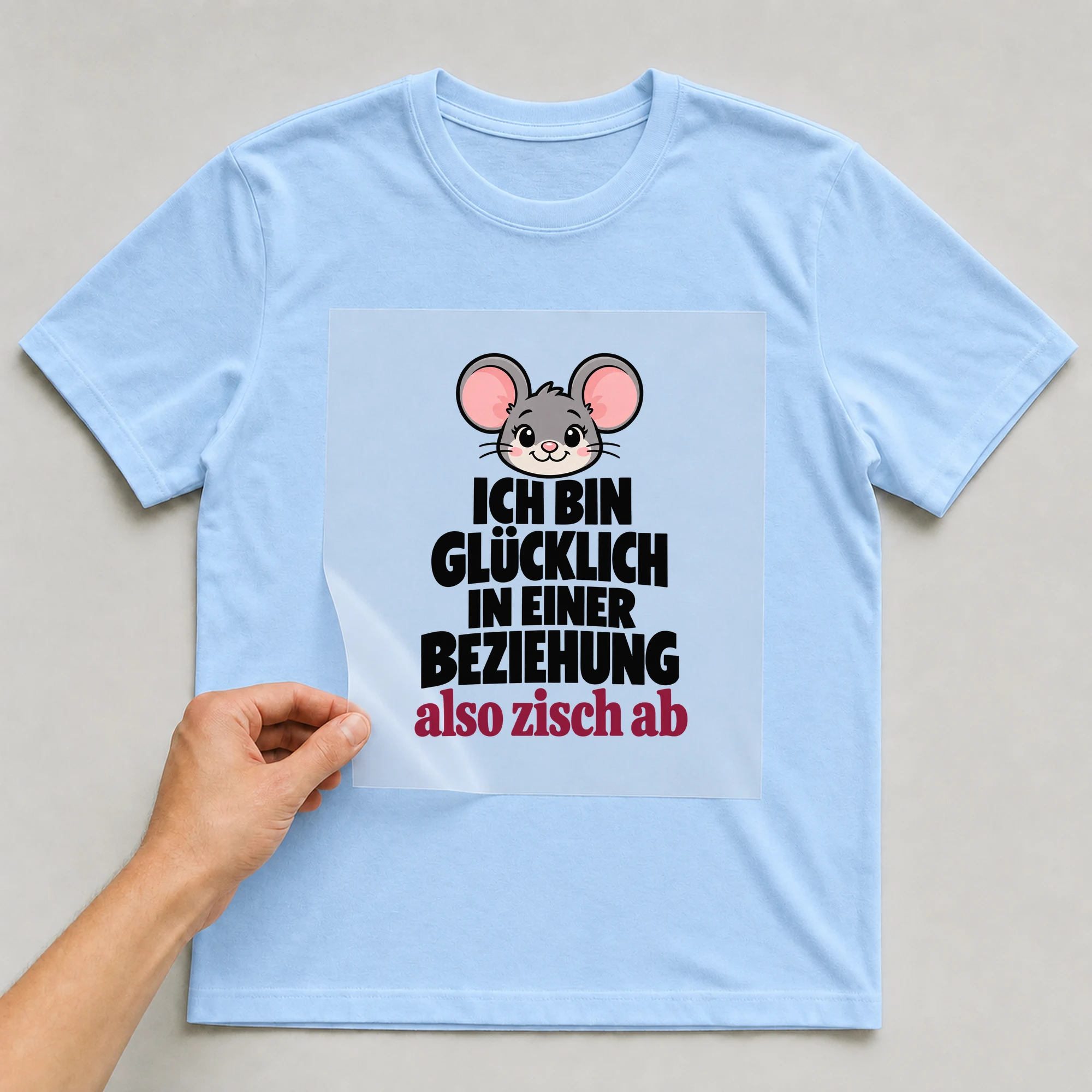 Bügelbild „Ich Bin Glücklich In Einer Beziehung Also Zisch Ab“ auf babyblauem T-Shirt, Folie wird aufgelegt