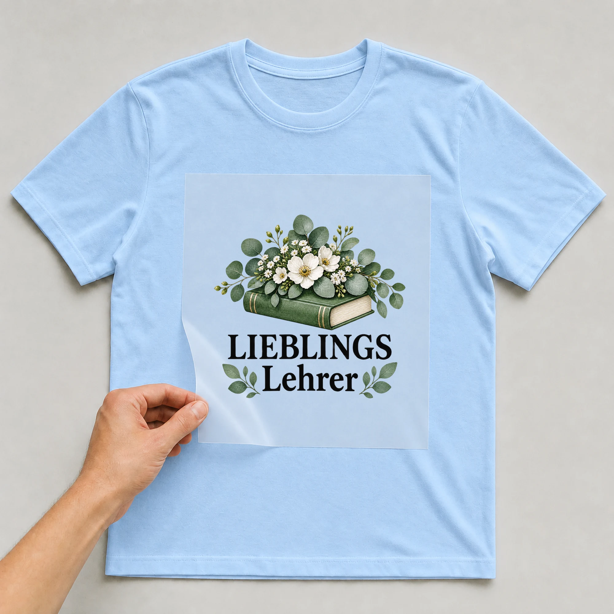Bügelbild „Lieblingslehrer“ auf babyblauem T-Shirt, Folie wird aufgelegt