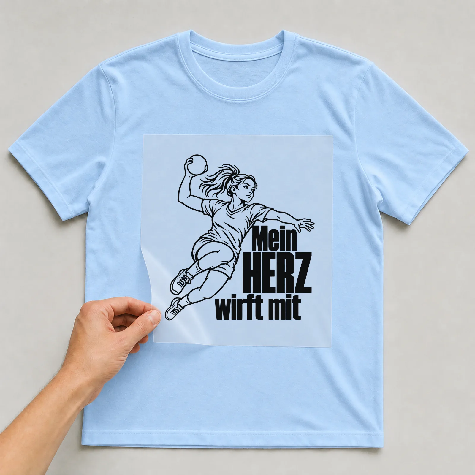 Bügelbild „Mein HERZ wirft mit“ (klaren Konturen) auf hellblauem T-Shirt, Folie wird aufgelegt